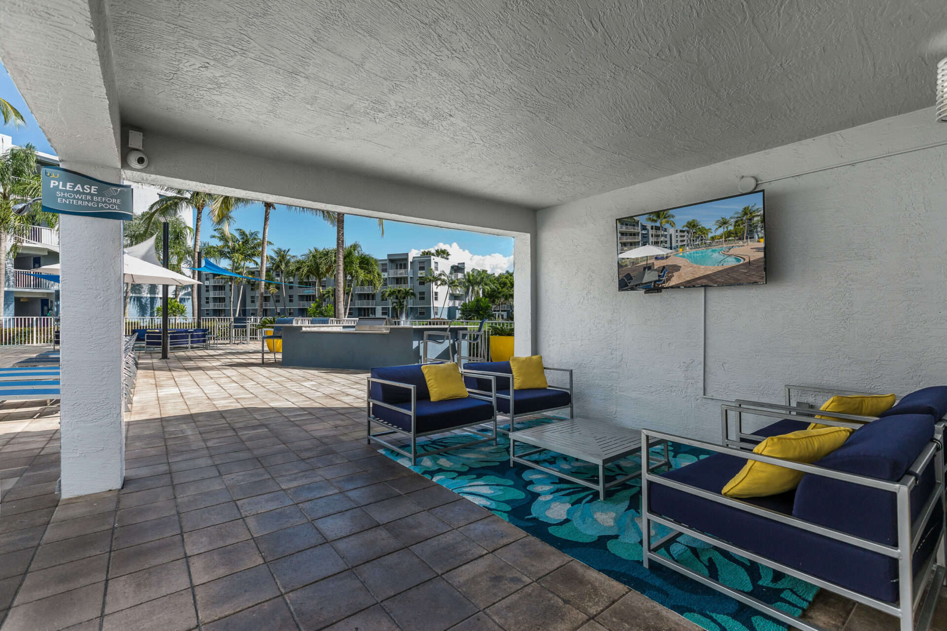 Outdoor pool area with a variety of seating options and an outdoor TV.