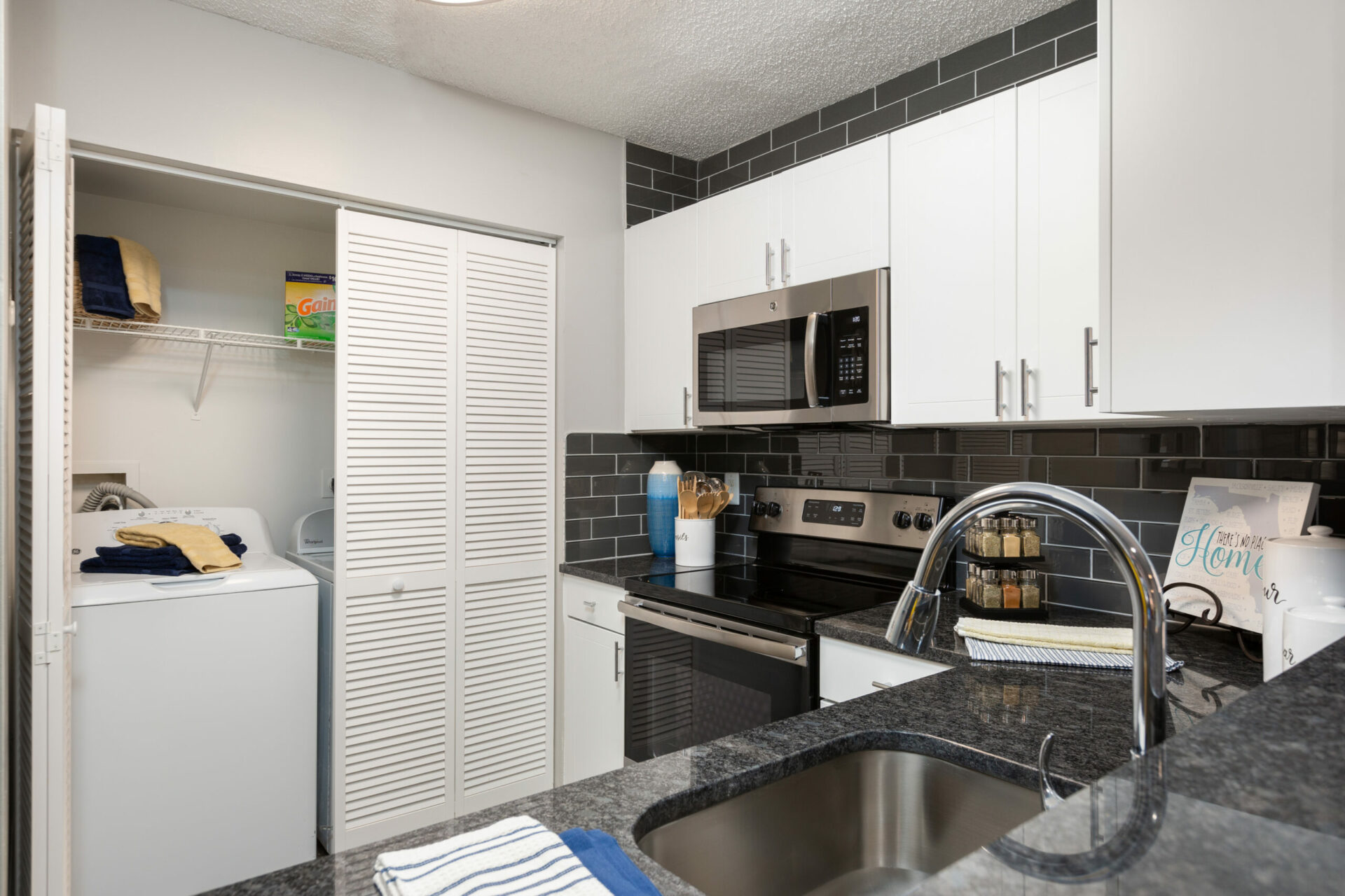 Kitchen with stainless steel appliances and separate washer and dryer section.