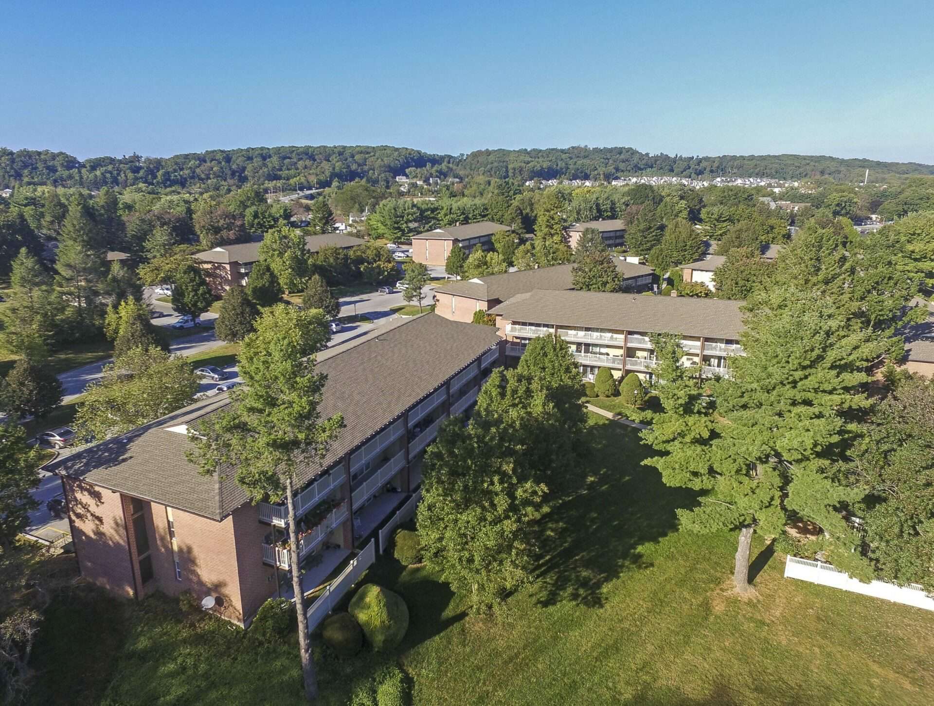 Exterior aerial view of apartments at Black Hawk apartments, fitted with a lawn, and tall trees