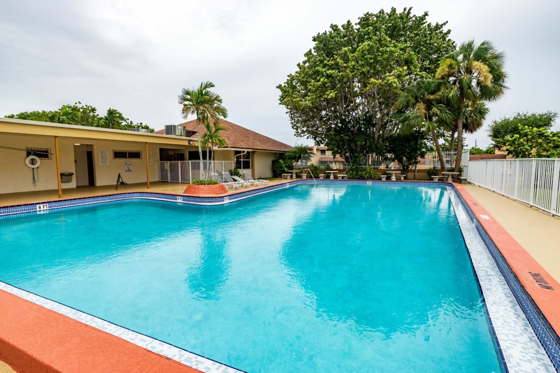 Fenced-in outdoor pool area with several seating options.