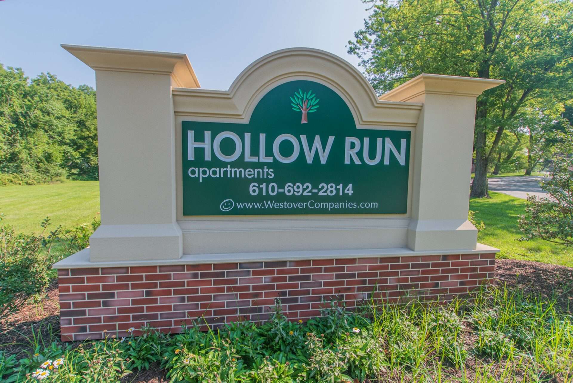 Hollow Run Apartments sign with grass and plants around it.
