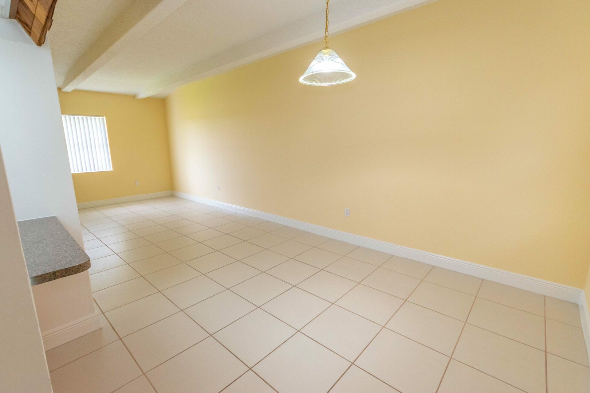 Spacious living and dining area with a hanging light and yellow walls at Green Briar West.