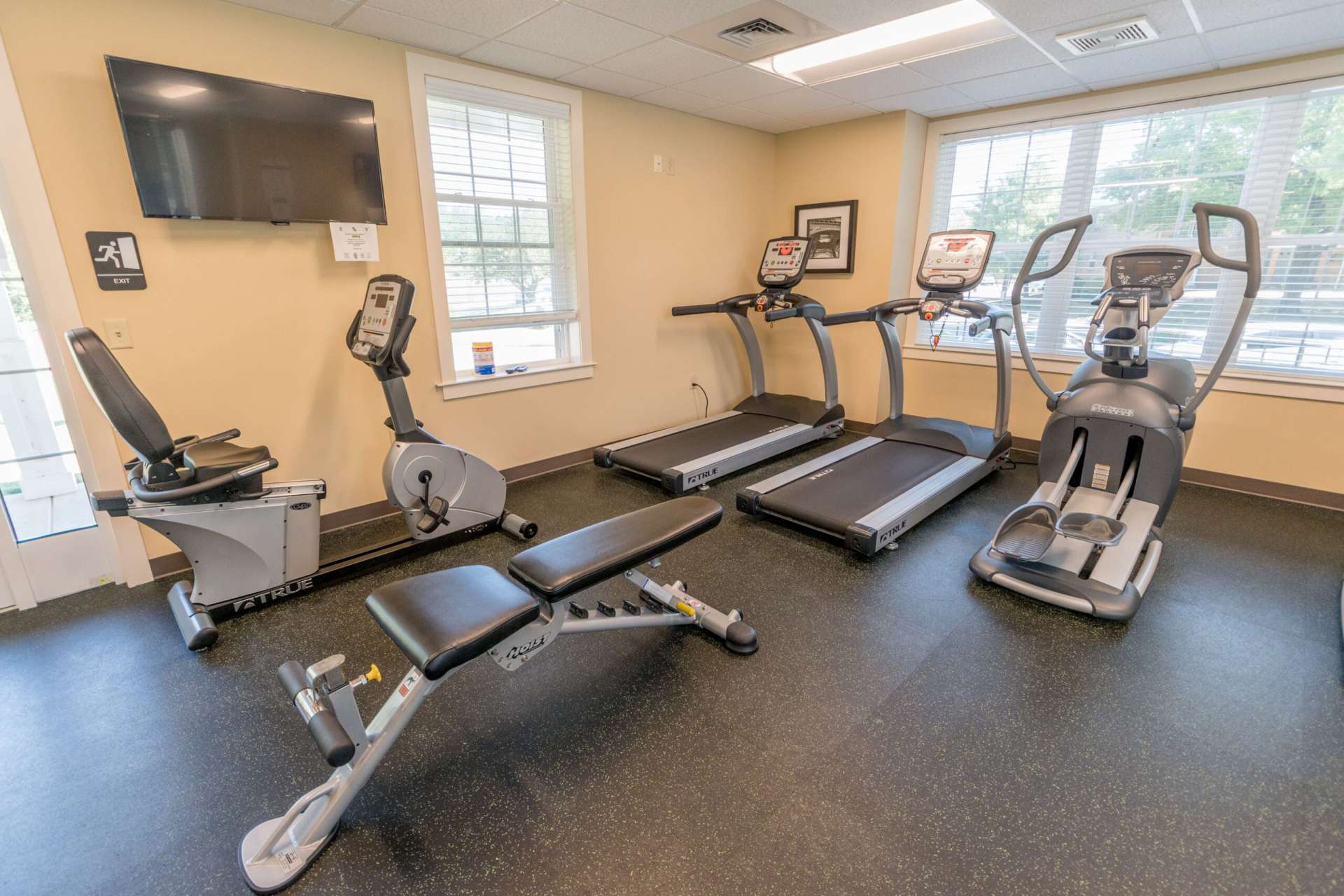 Indoor gym at Independence Crossing Apartments with a variety of workout equipment and large windows.