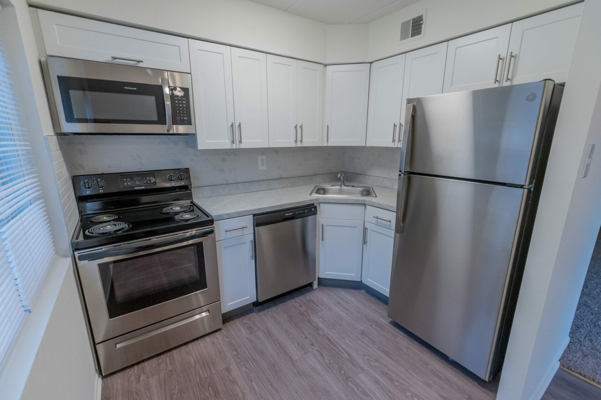 Kitchen area of an apartment, fitted with vinyl flooring, stainless steel appliances, and spacious cabinets