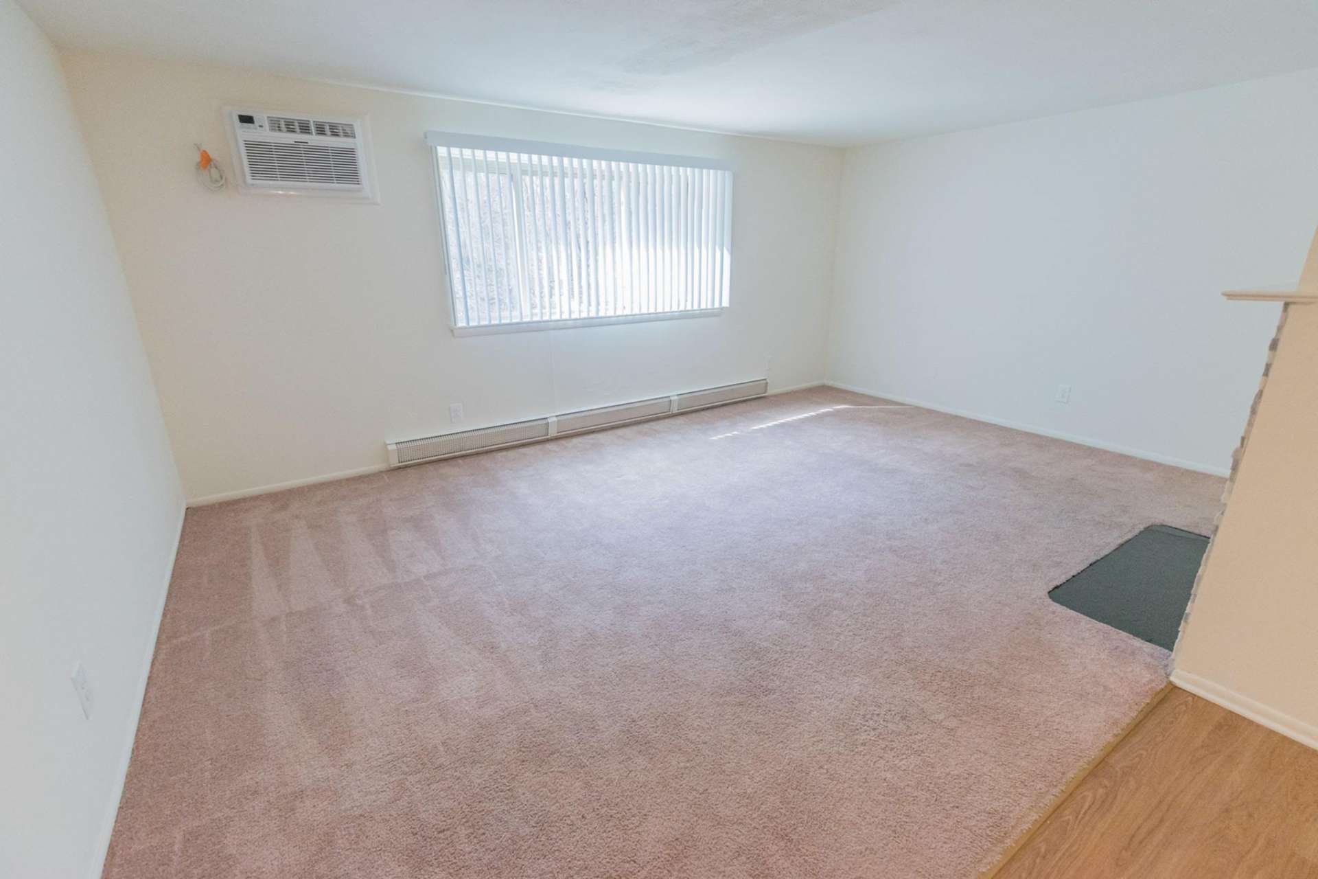 Living room space with light pink carpet and a large window in an apartment at Hollow Run.