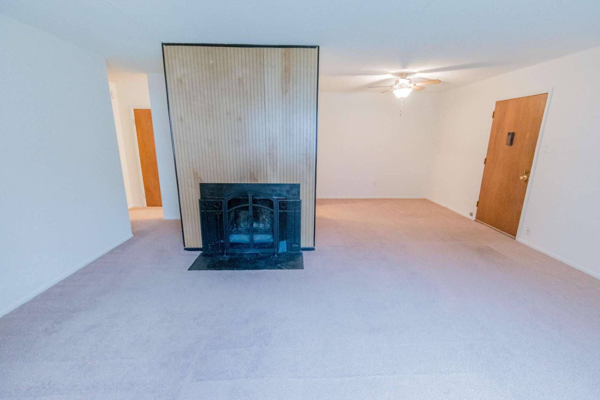 Carpeted living room with a fireplace and a ceiling fan in an apartment at Hollow Run.