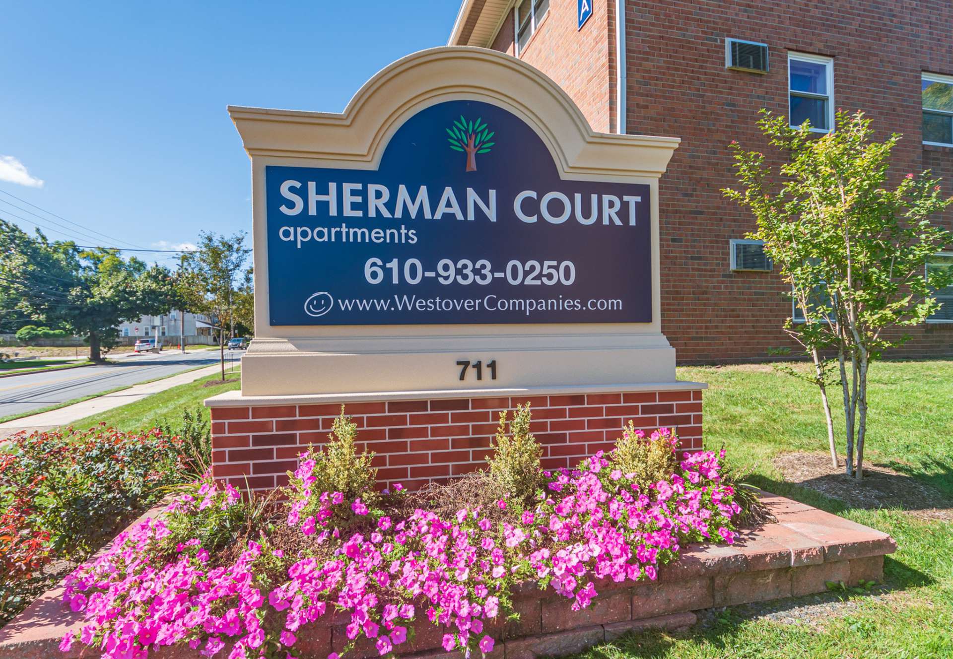 Sherman Court Apartments sign with various flowers around the sign.