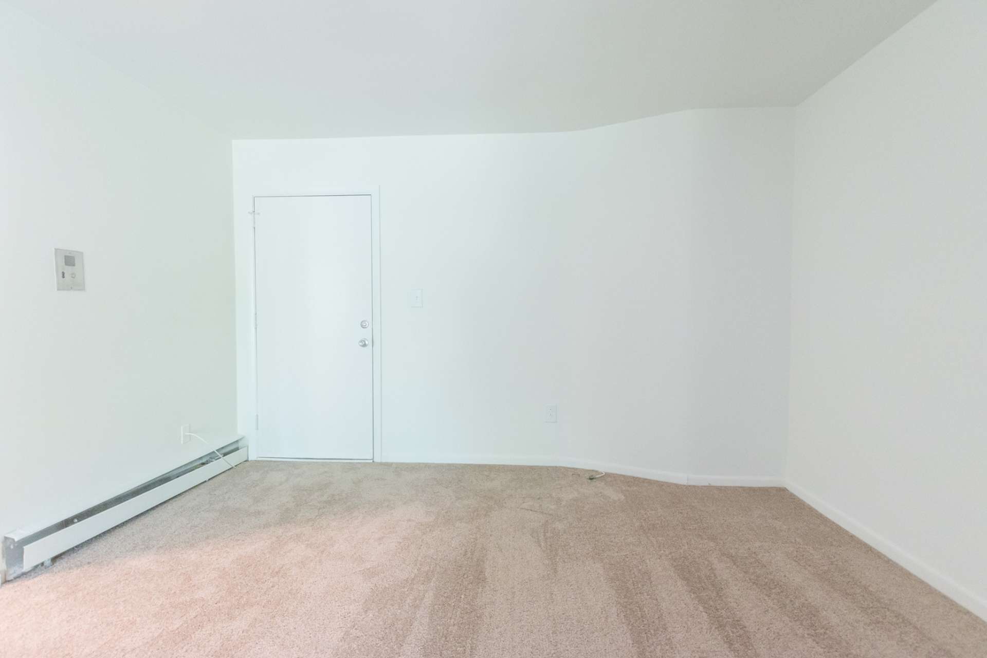 Spacious living area with light beige carpets in Sherman Court Apartments.