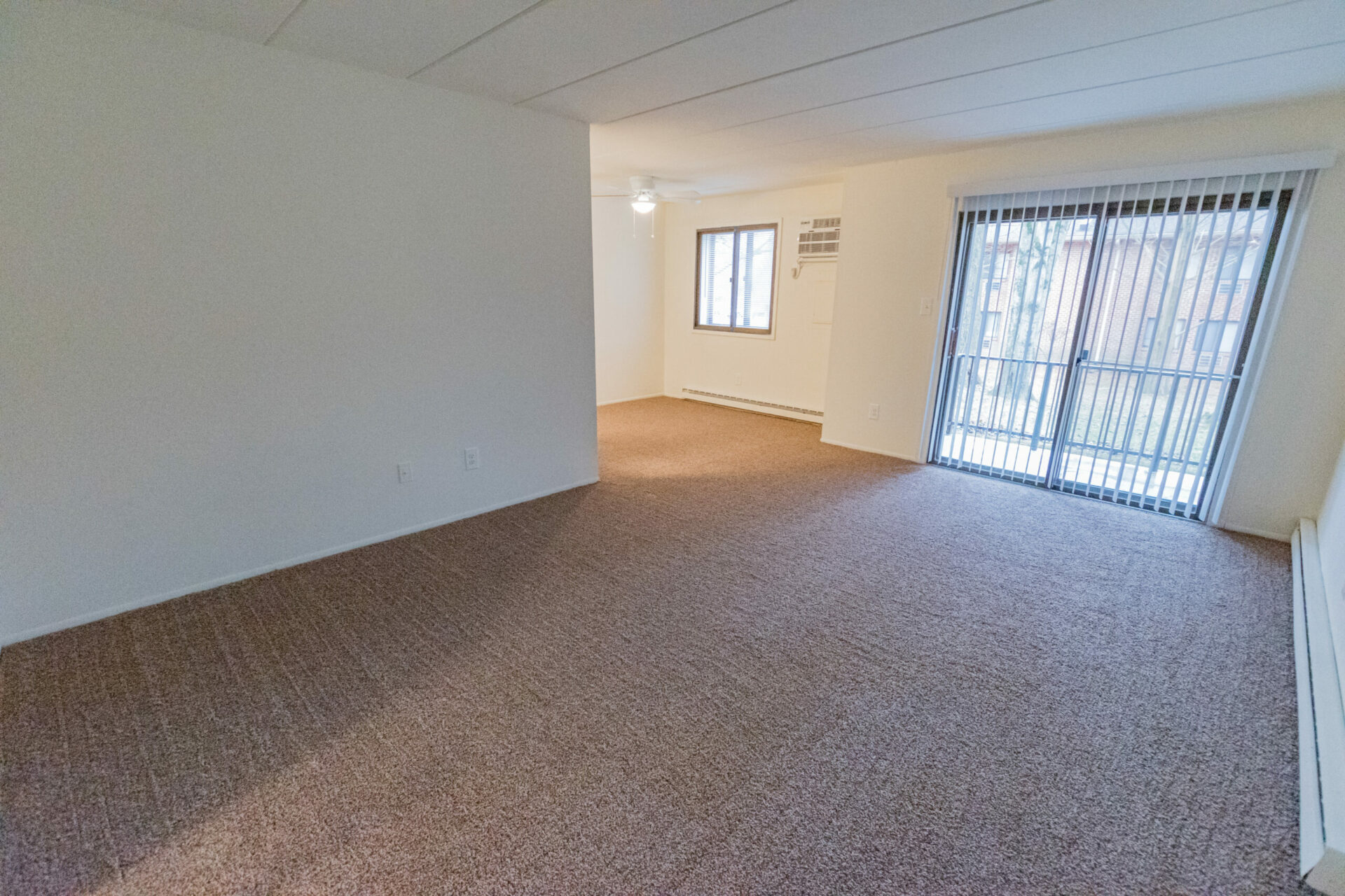 Carpeted living room with sliding door leading to balcony at Whiteleand West Apartments