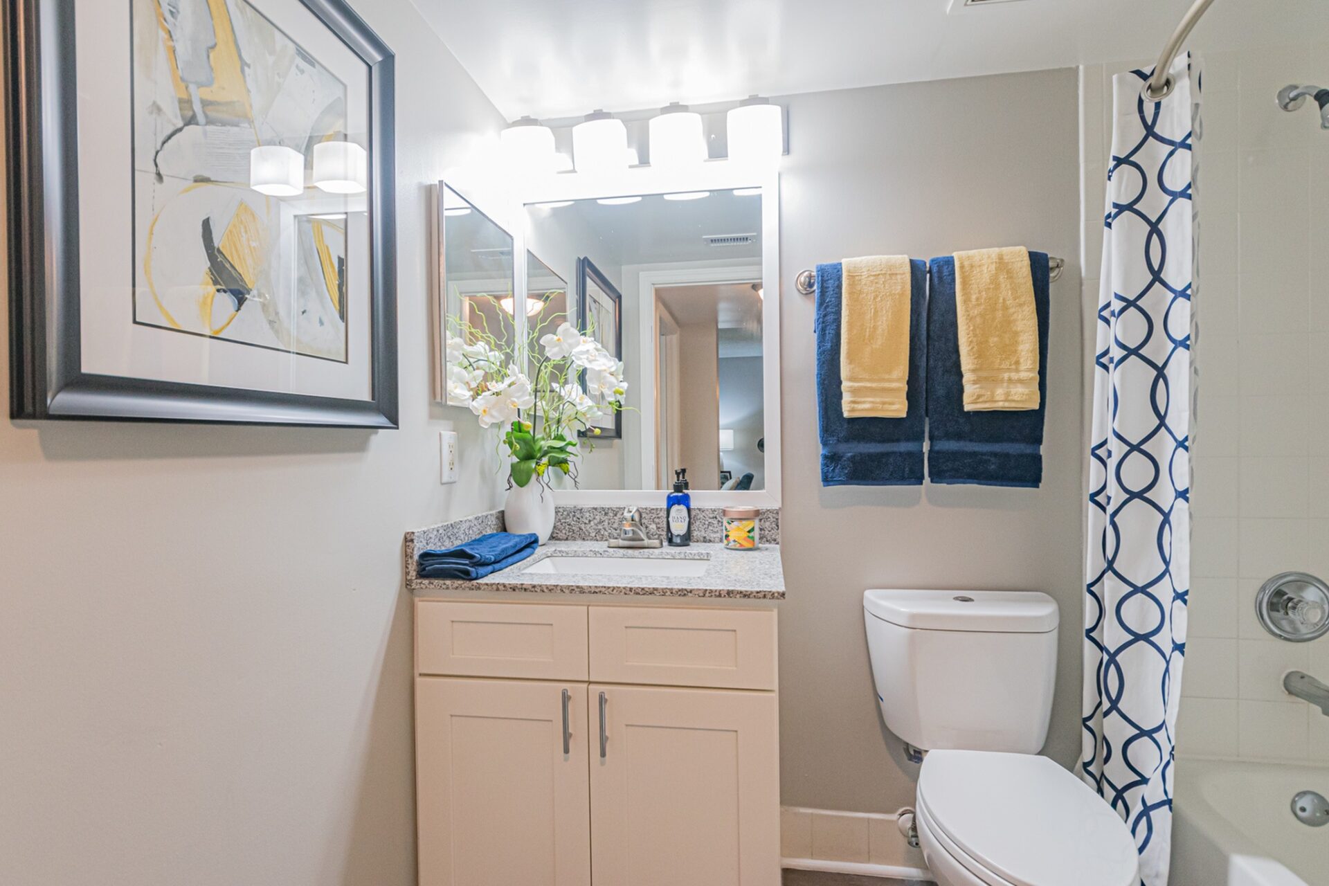Bathroom with white cabinets, a tub, and a large mirror at an apartment at Beach Walk at Sheridan.