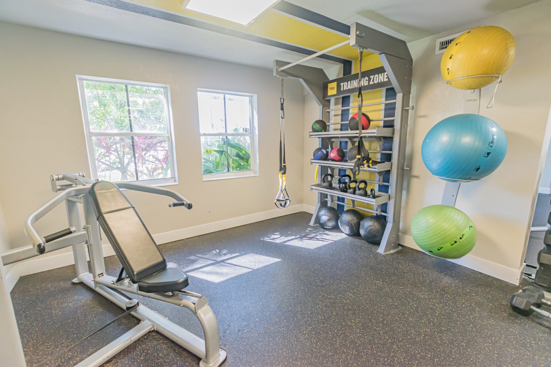 Indoor gym with a variety of workout equipment and 2 windows.