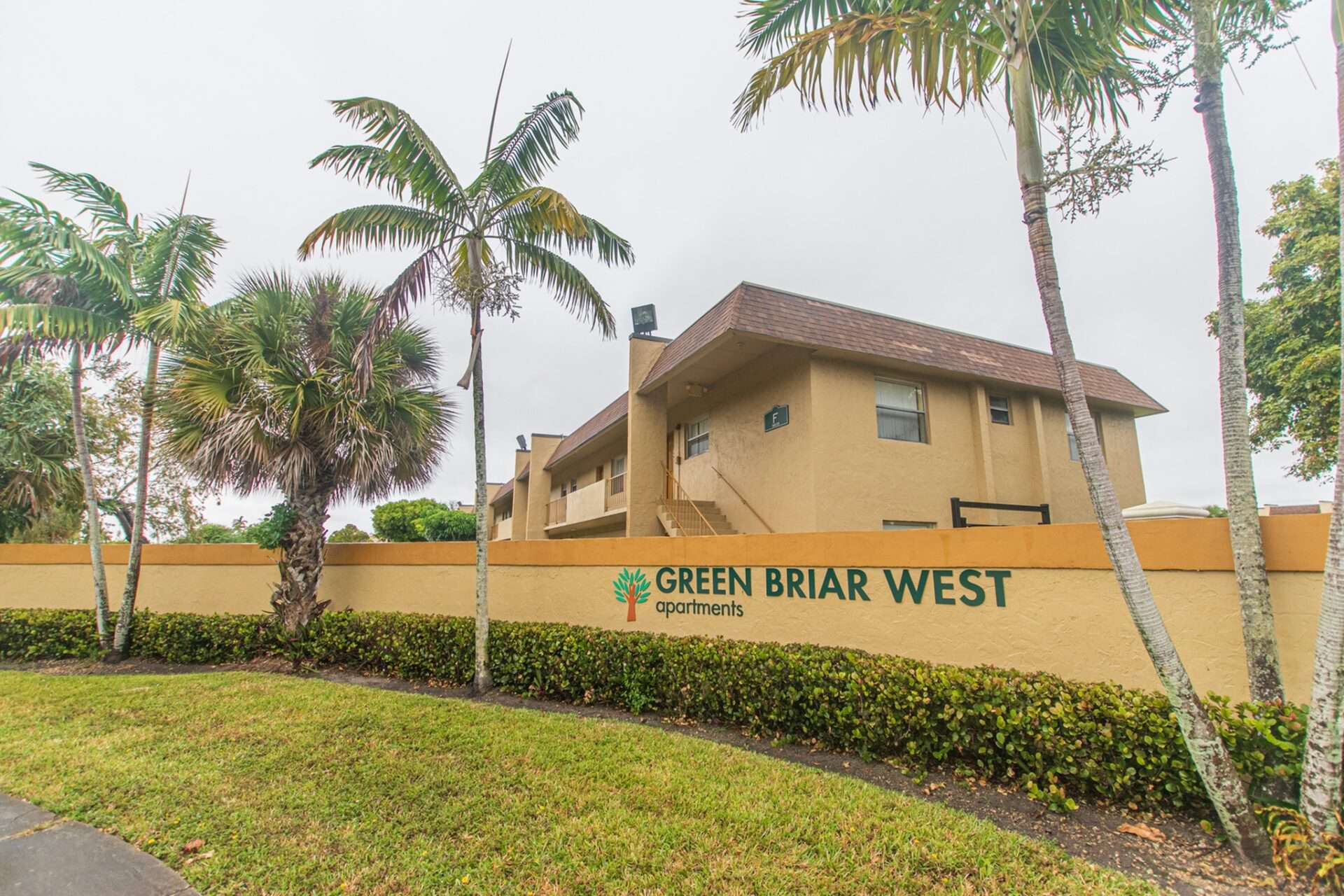 Sign saying "Green Briar West apartments" with palm trees beside it.
