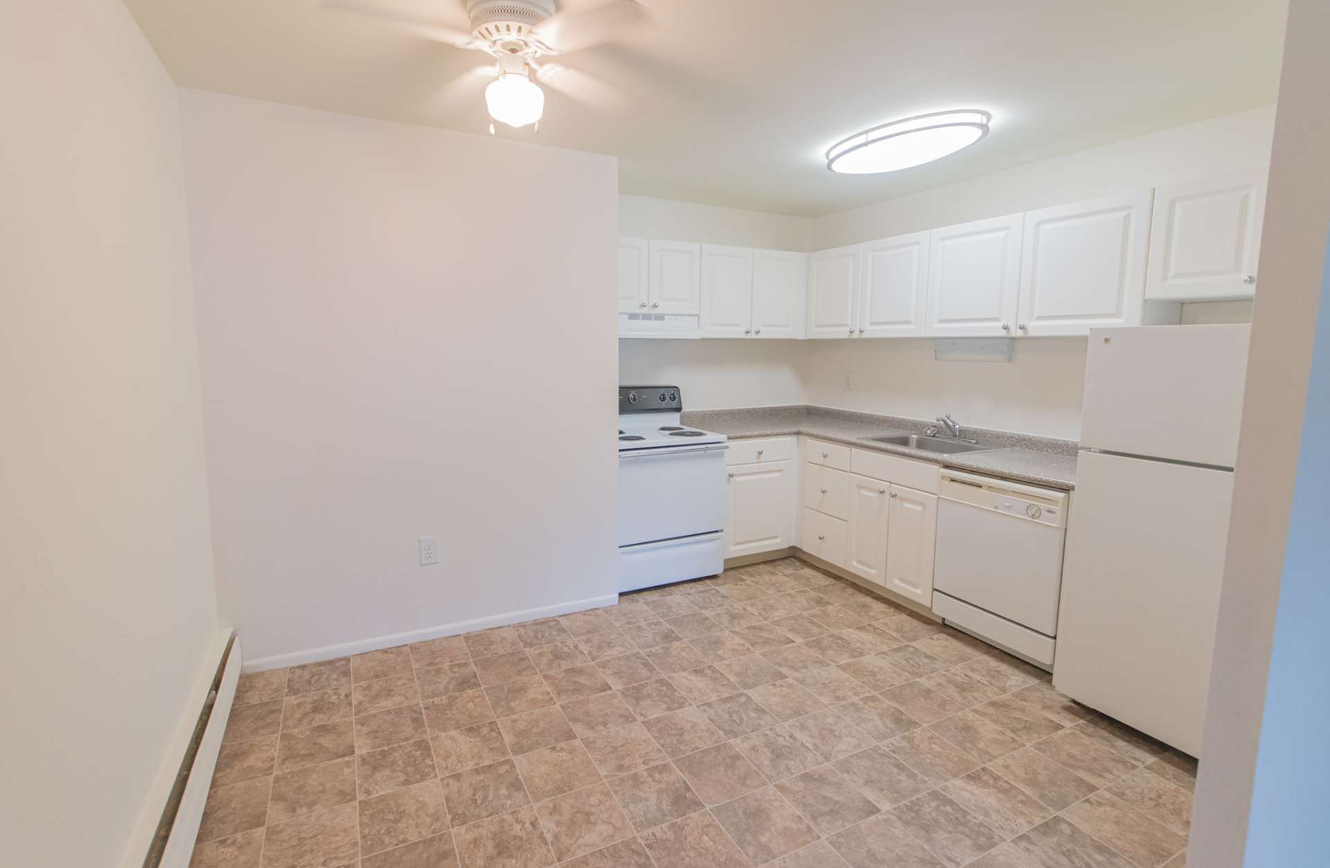 Spacious kitchen and dining area with a ceiling fan and light brown tile flooring.