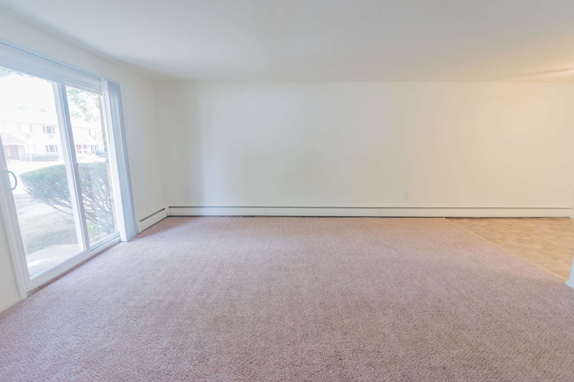 Spacious carpeted living room with sliding window doors.
