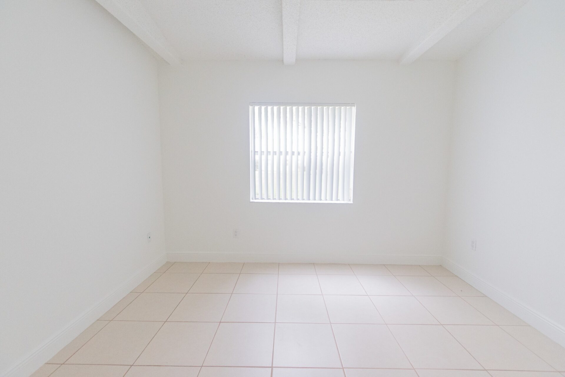 Room with white tile flooring and window.