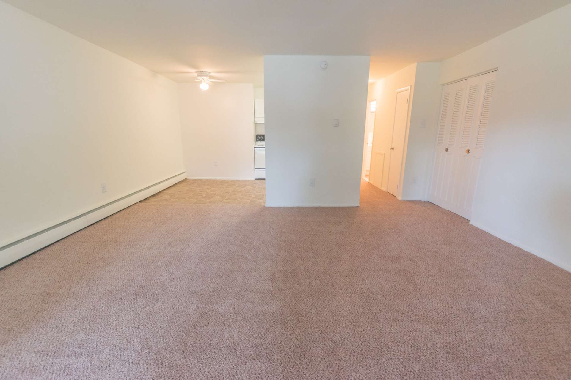 Carpeted living room area connected to the dining and kitchen area in a West Chester, PA apartment.