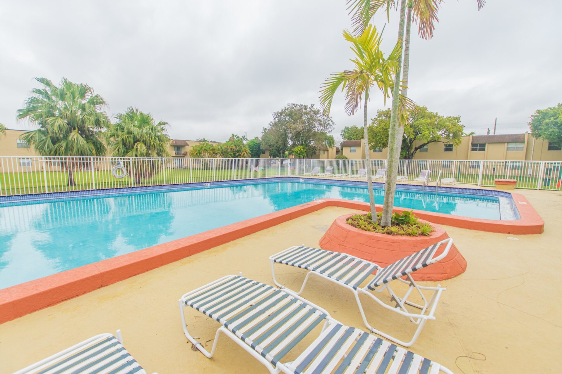 Fenced-in outdoor pool with a variety of seating options at Green Briar West apartments.