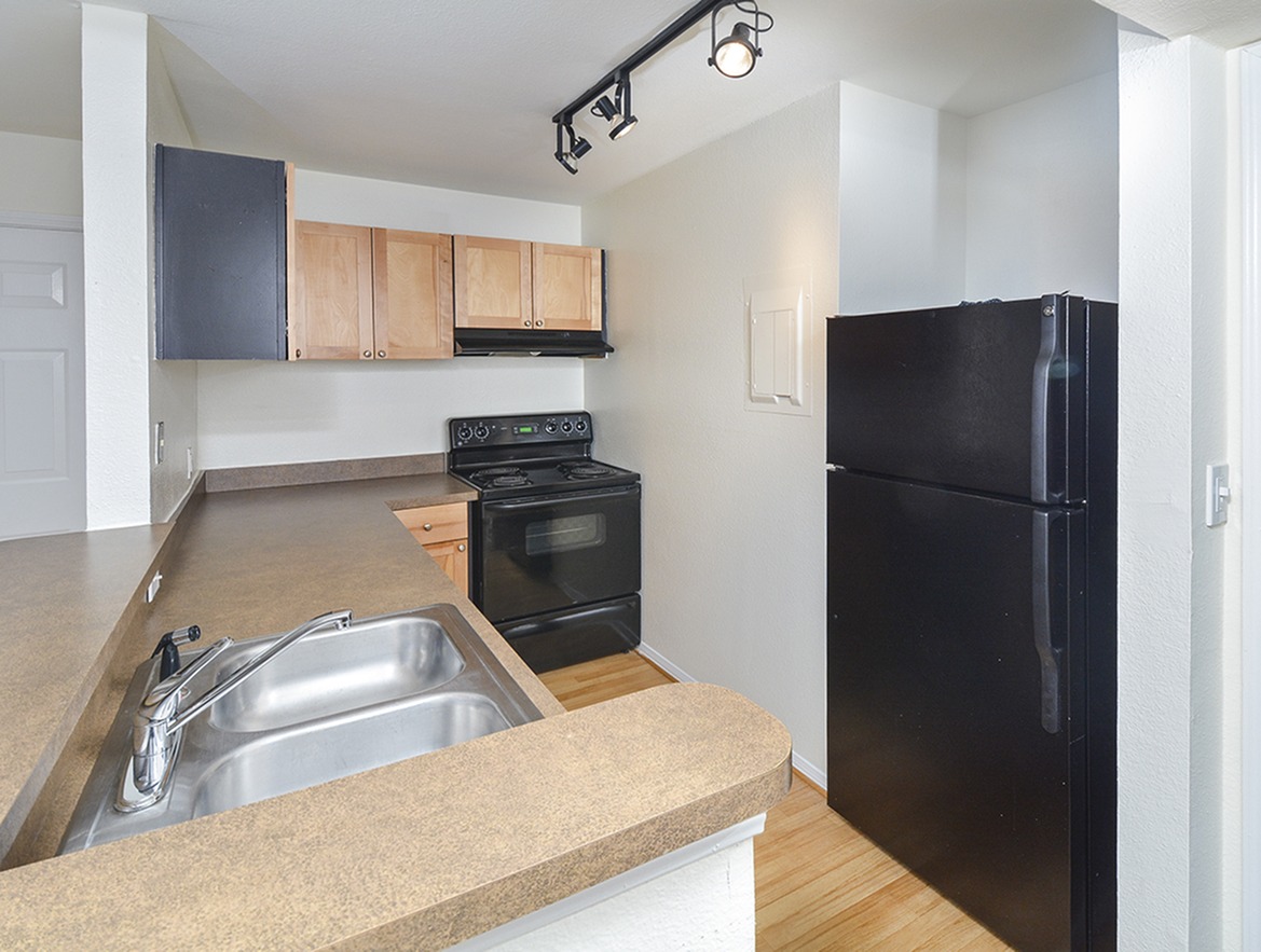 A kitchen with wood cabinets and black appliances at Waterloo Place Apartments
