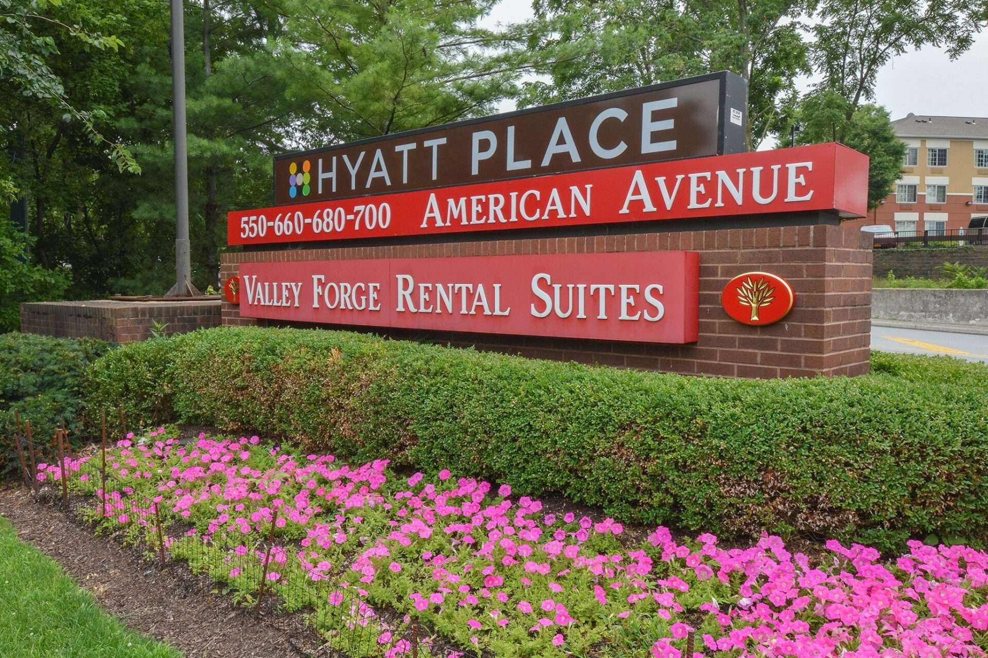 Sign for Valley Forge Suites with flowers in the front of it.