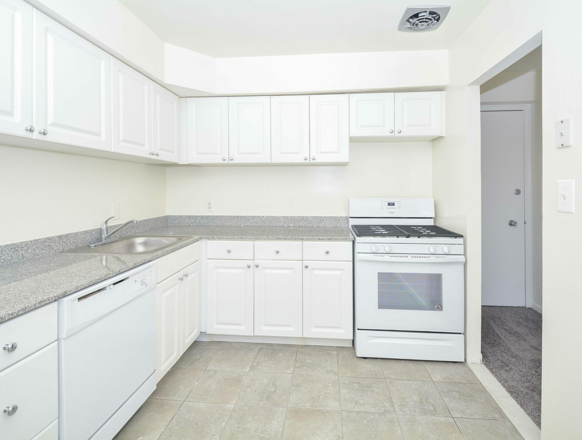 Kitchen area with white cabinets and white appliances.