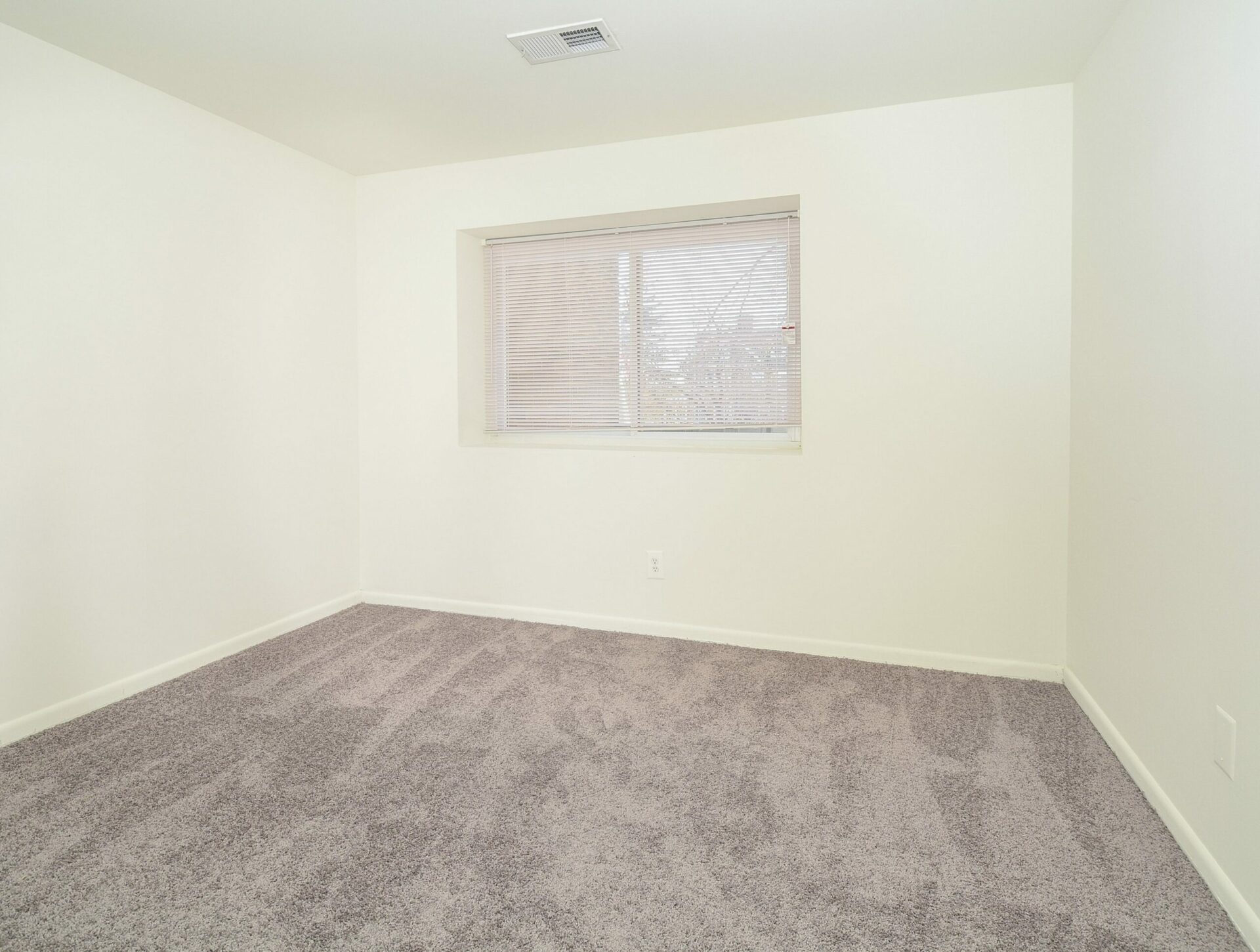 Bedroom with grey carpets, a window, and white walls at Main Line Berwyn.