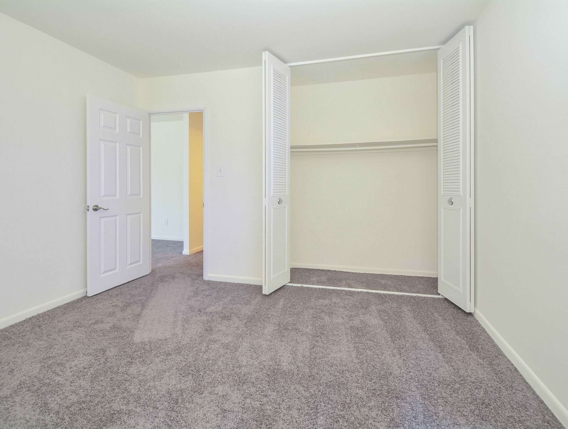 Bedroom with grey carpet and a large closet.