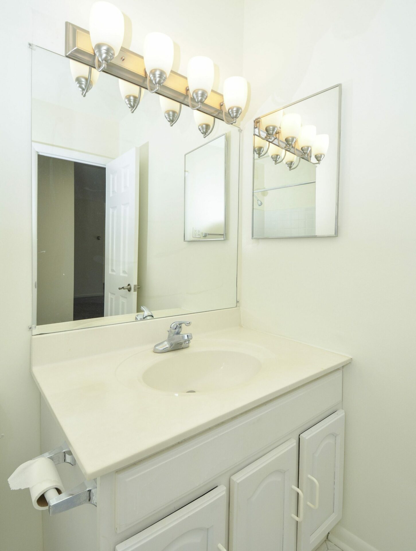 Bathroom with a large mirror, a sink with white countertops and cabinets, and vanity lights.