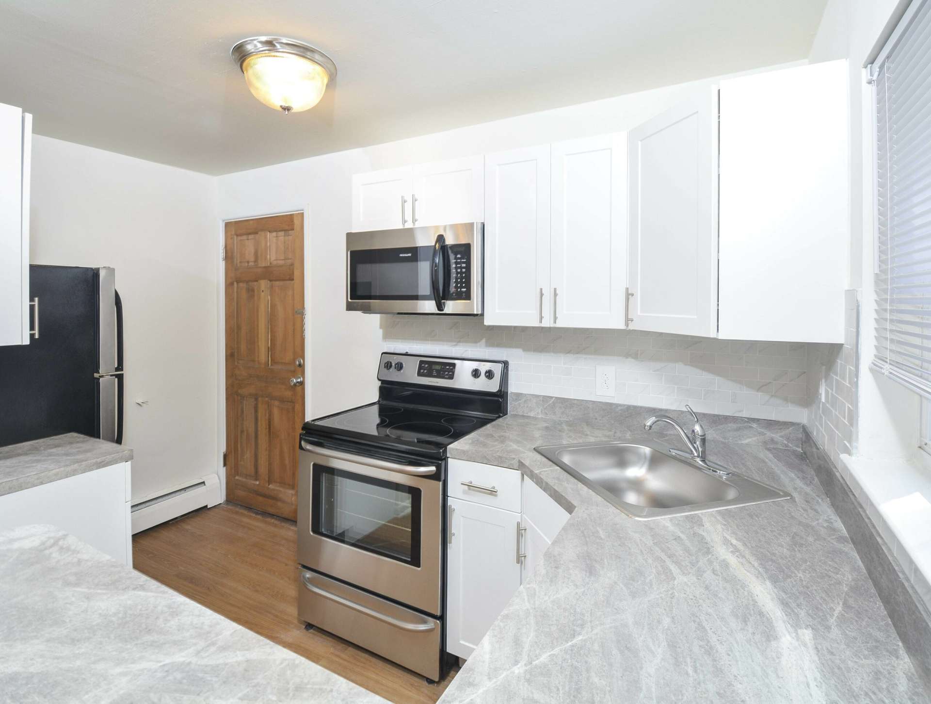 Kitchen with white cabinets, stainless steel appliances, and hardwood flooring.