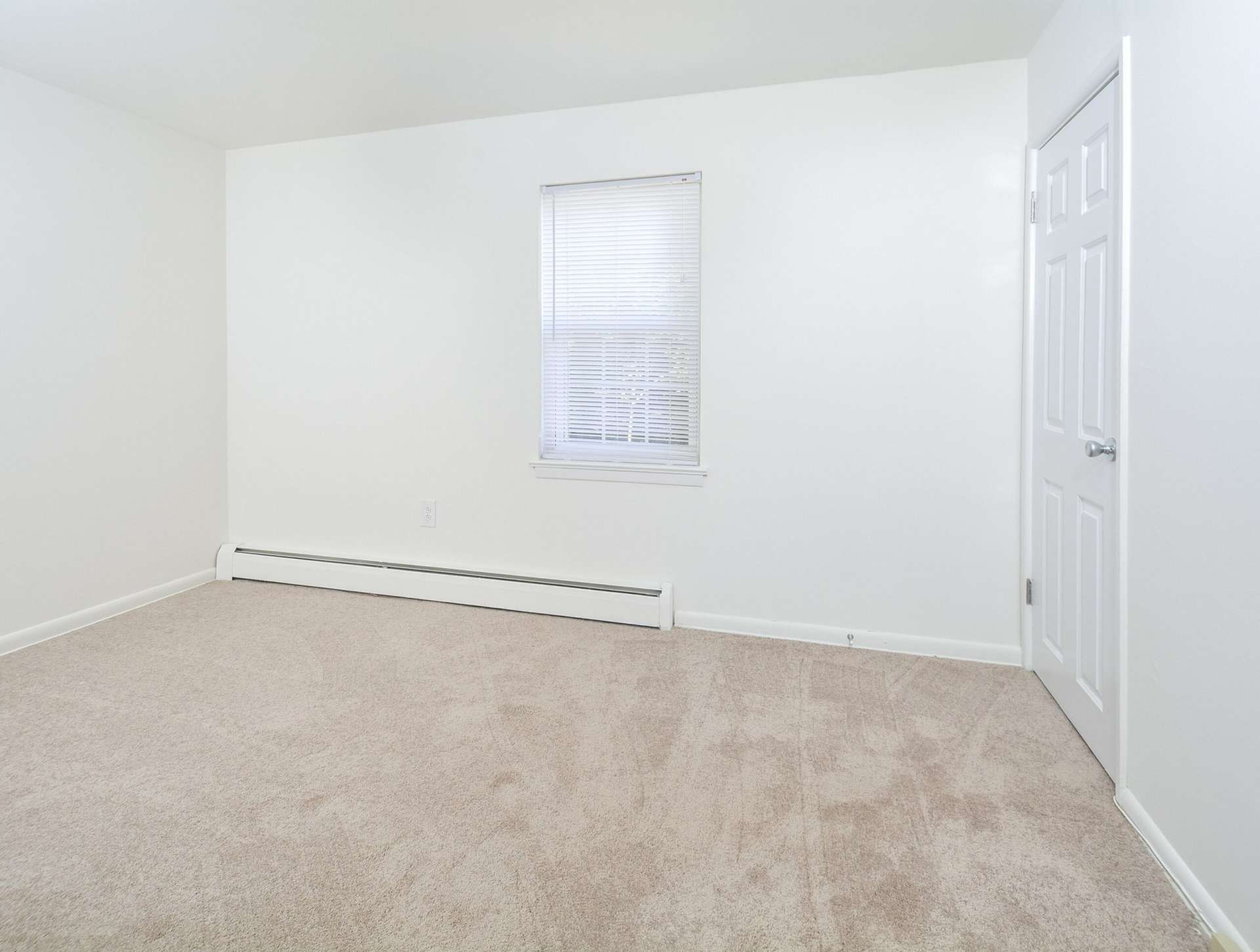 Bedroom with beige carpets, white walls, and a window.