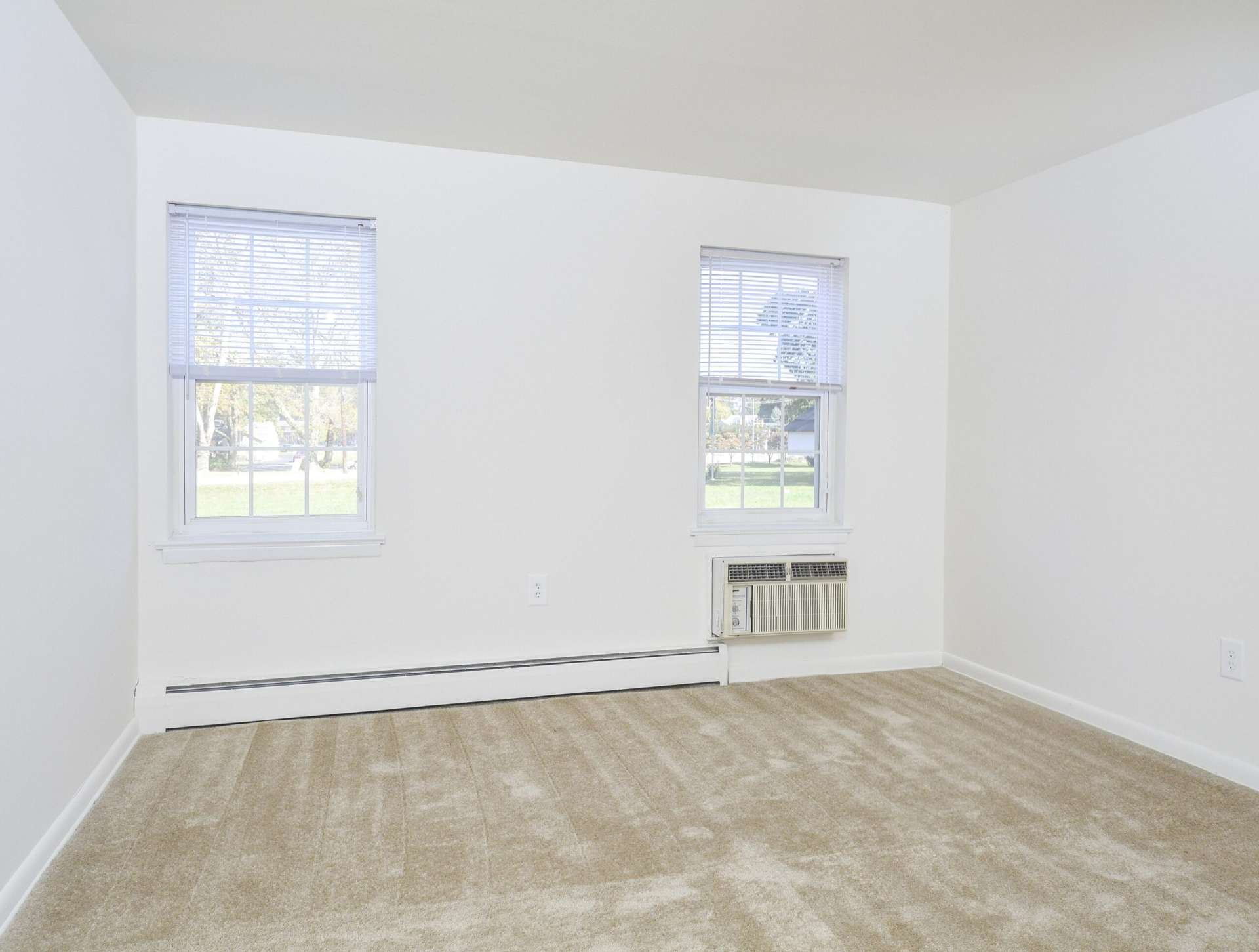 Bedroom with beige carpets and 2 windows at Knollwood Apartments.