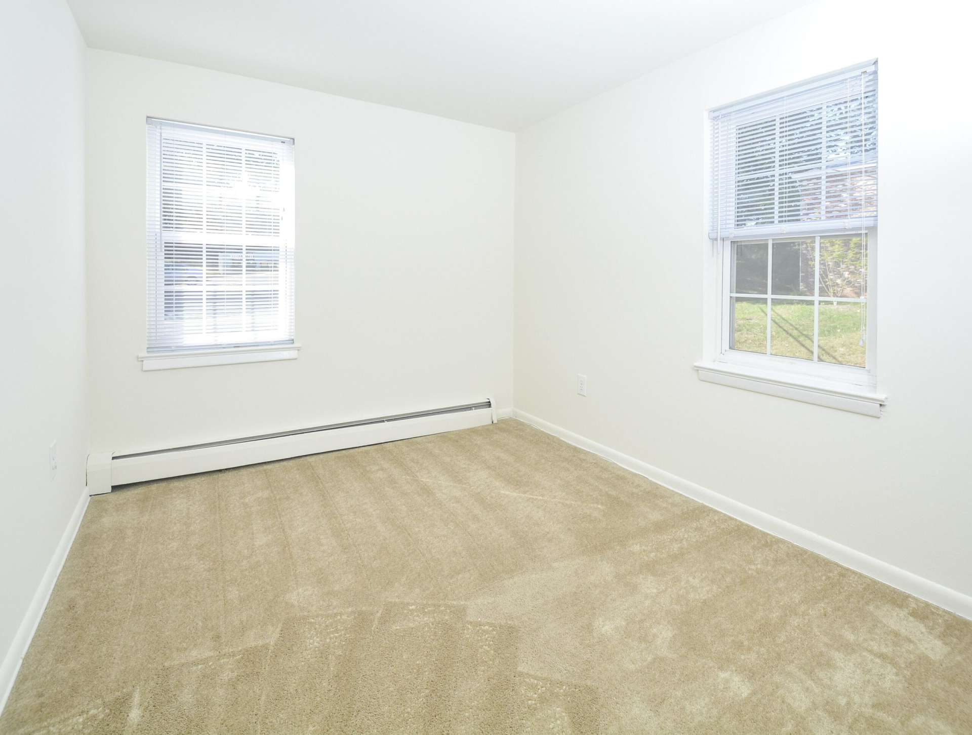 Bedroom with beige carpets, white walls, and 2 windows.