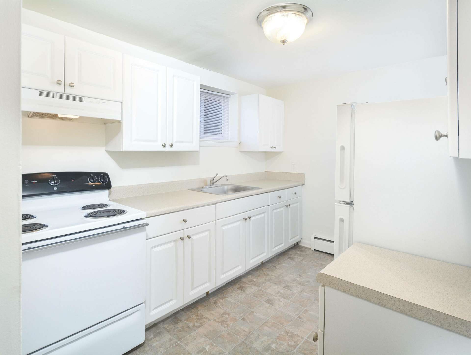 Kitchen area with white appliances, white cabinets, and a ceiling light.