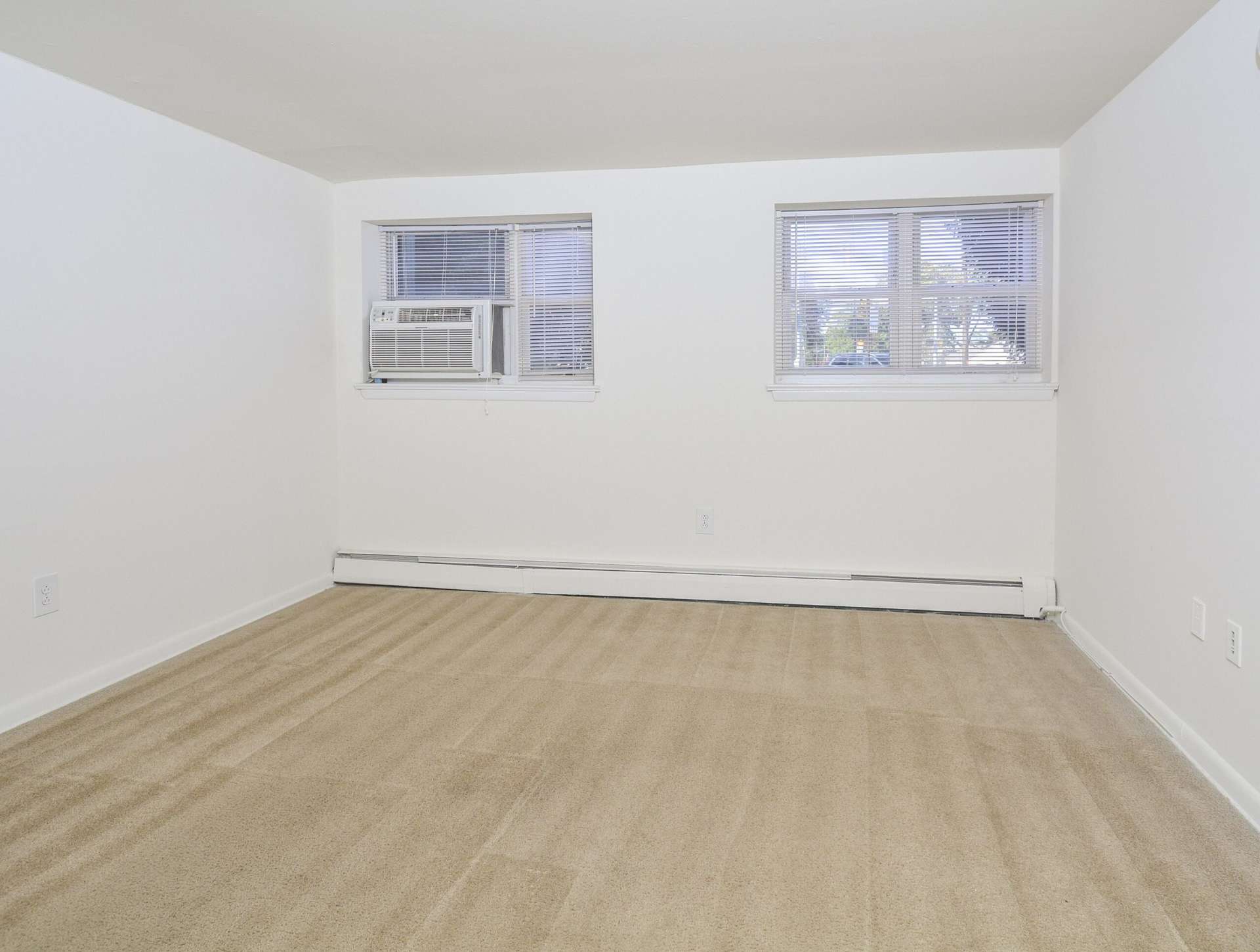 Bedroom with beige carpets, 2 windows, and white walls at Knollwood Apartments.