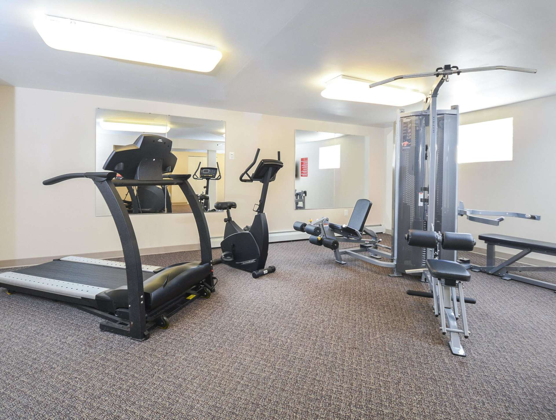 A variety of workout equipment with 2 large mirrors.