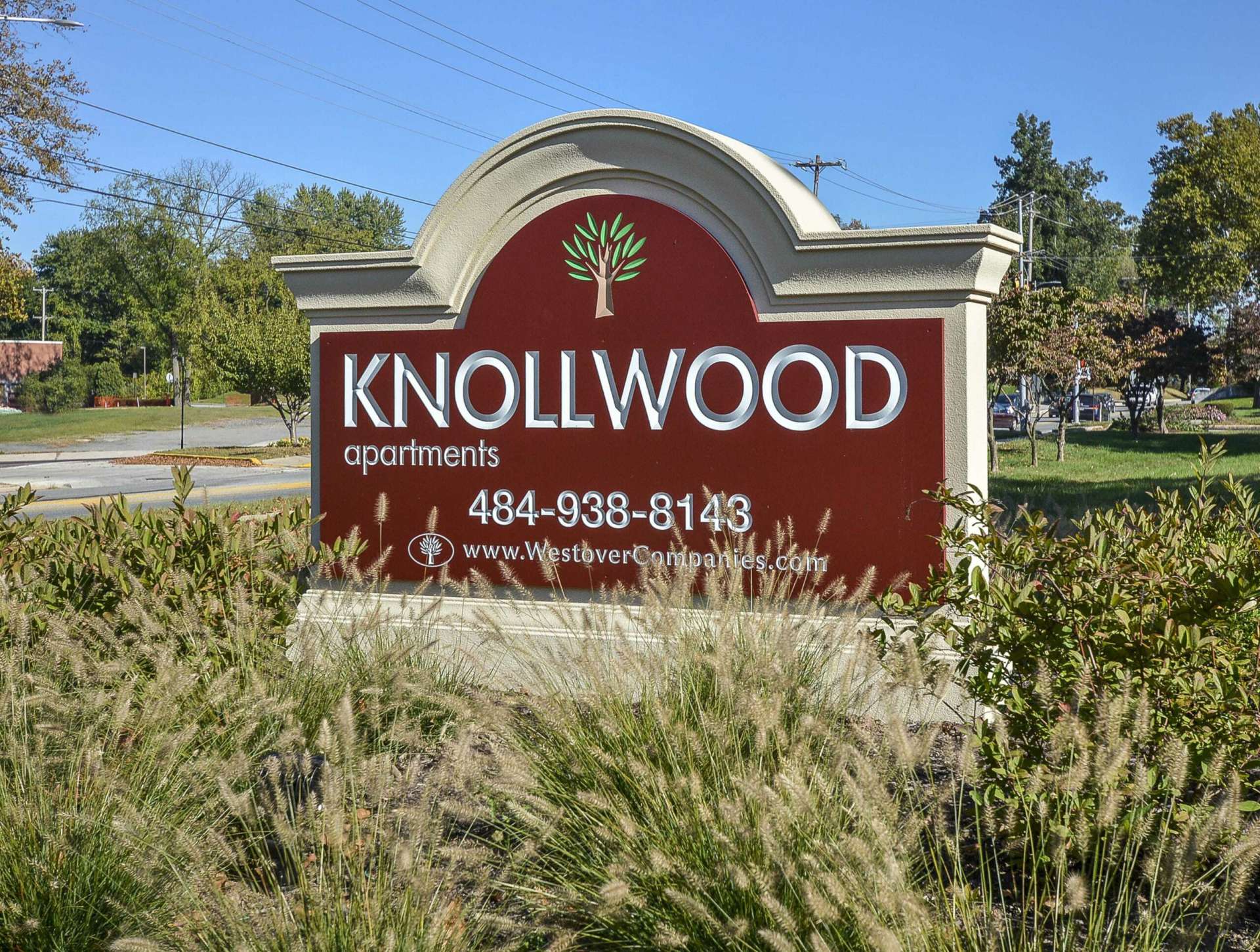 Knollwood Apartments sign with various bushes in front of the sign.