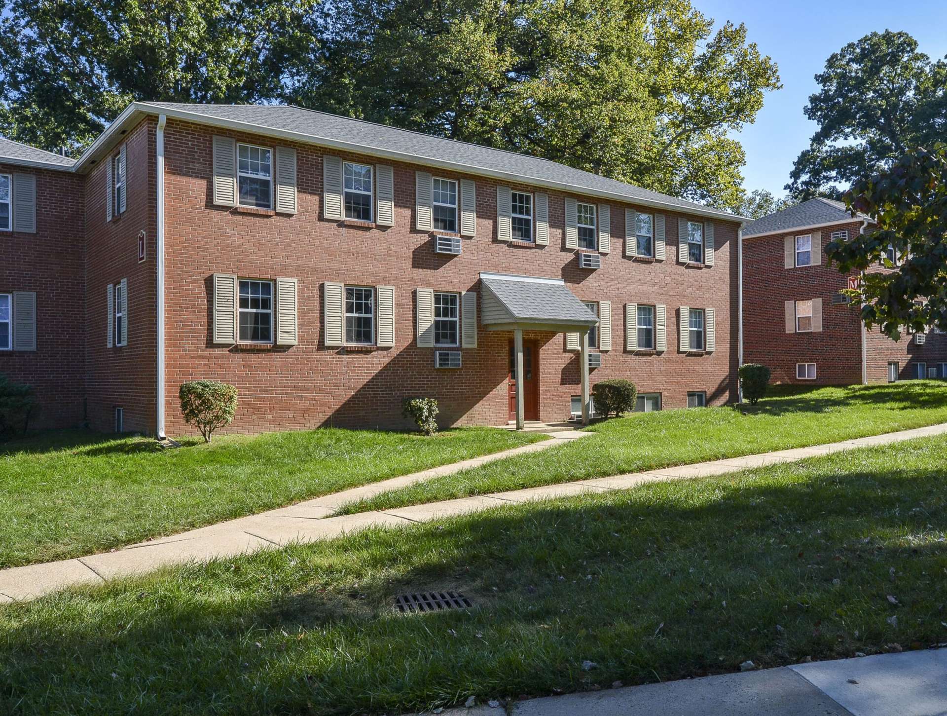 Knollwood apartment buildings with grass and sidewalks in front of them.