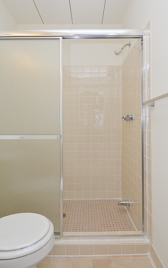 Shower with light beige tiles and glass doors.
