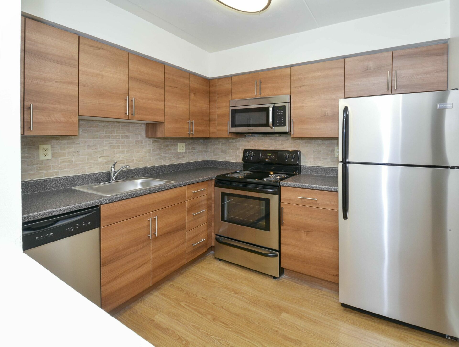 a modern kitchen with brown cabinets and stainless steel appliances at Valley Forge Suites