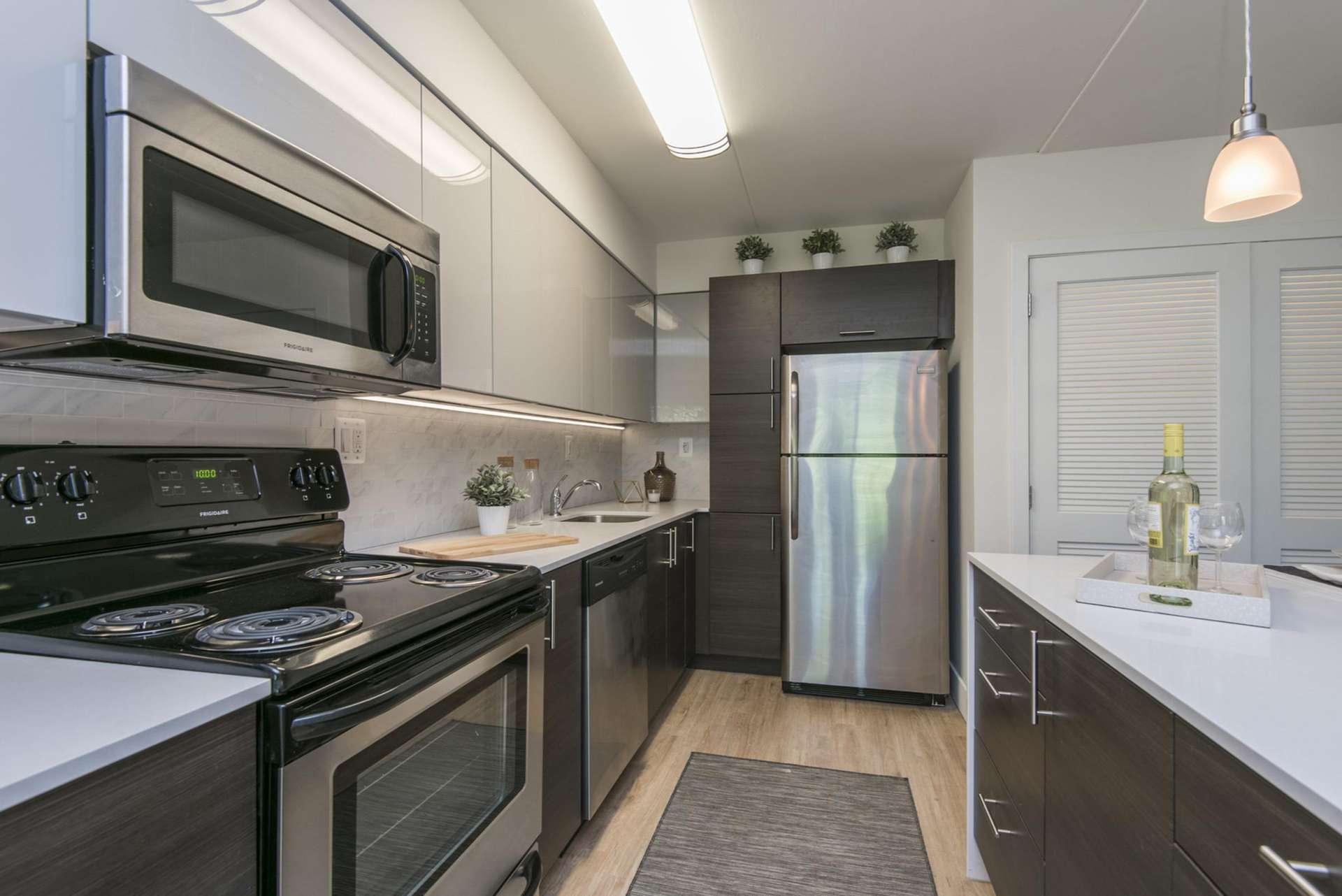Kitchen with stainless steel appliances, hanging lights, and plenty of cabinet space at Gulph Mills Village Apartments.