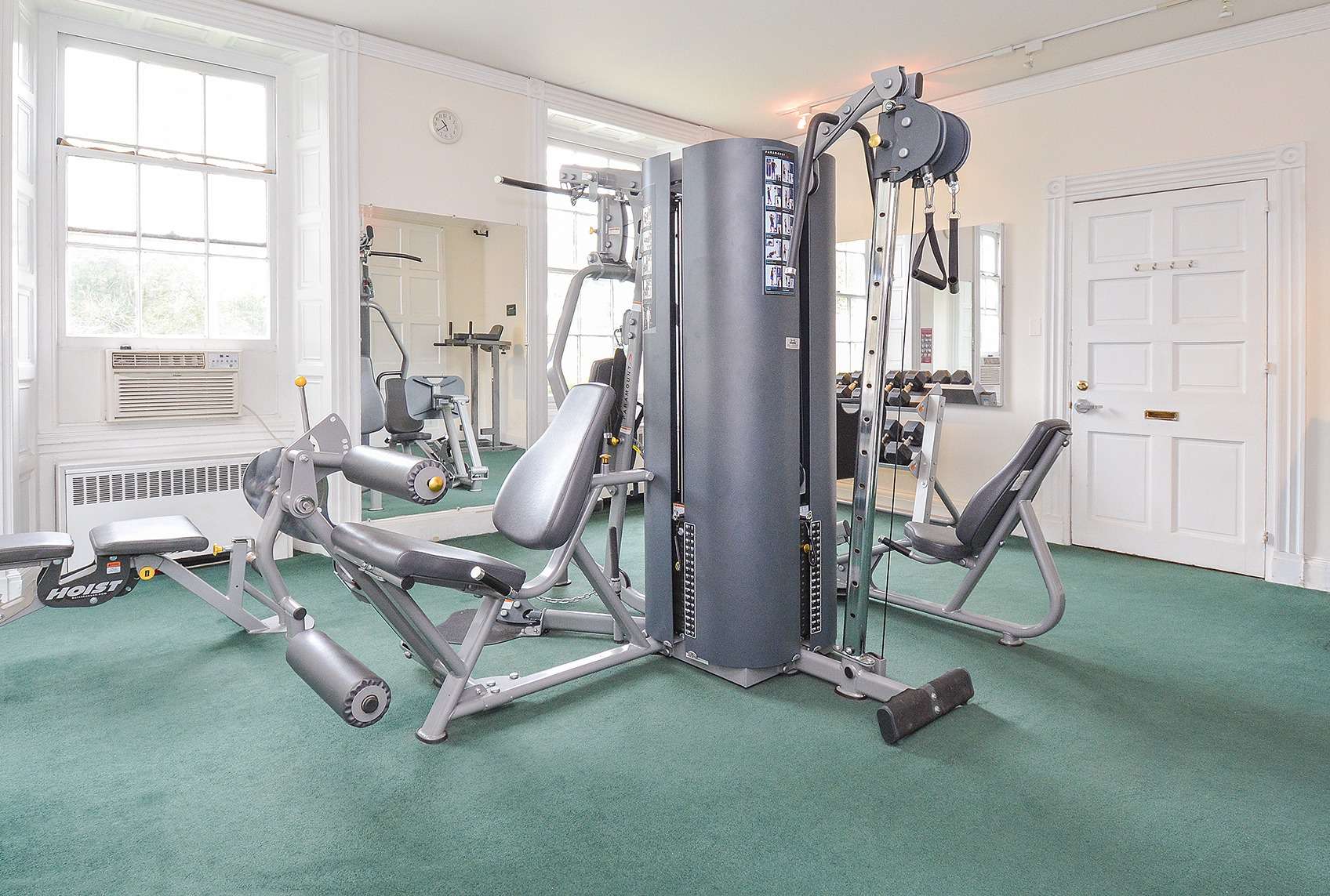 Indoor gym at Gulph Mills Village Apartments with windows, a mirror, and various workout equipment.