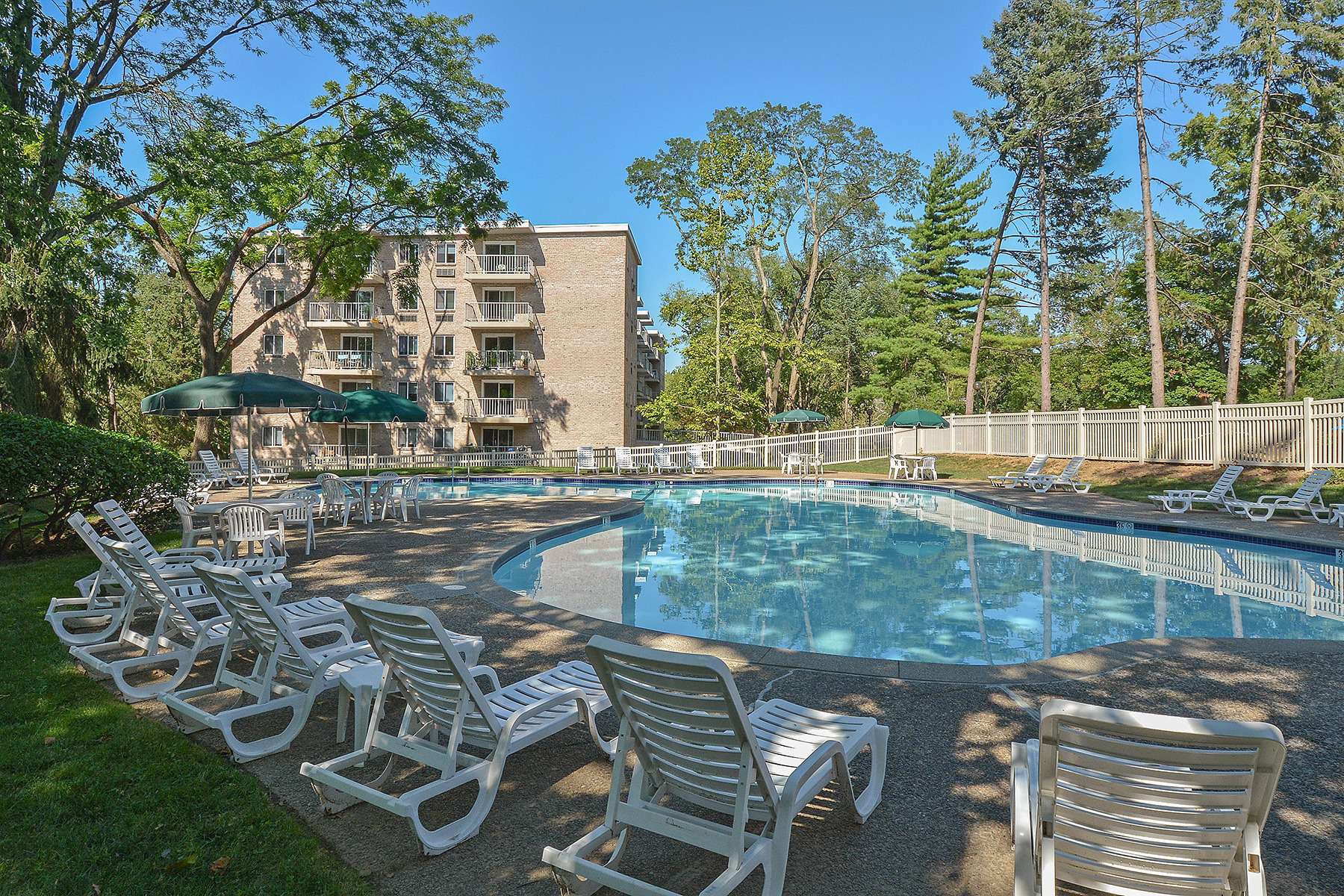 Fenced-in pool area surrounded by trees.