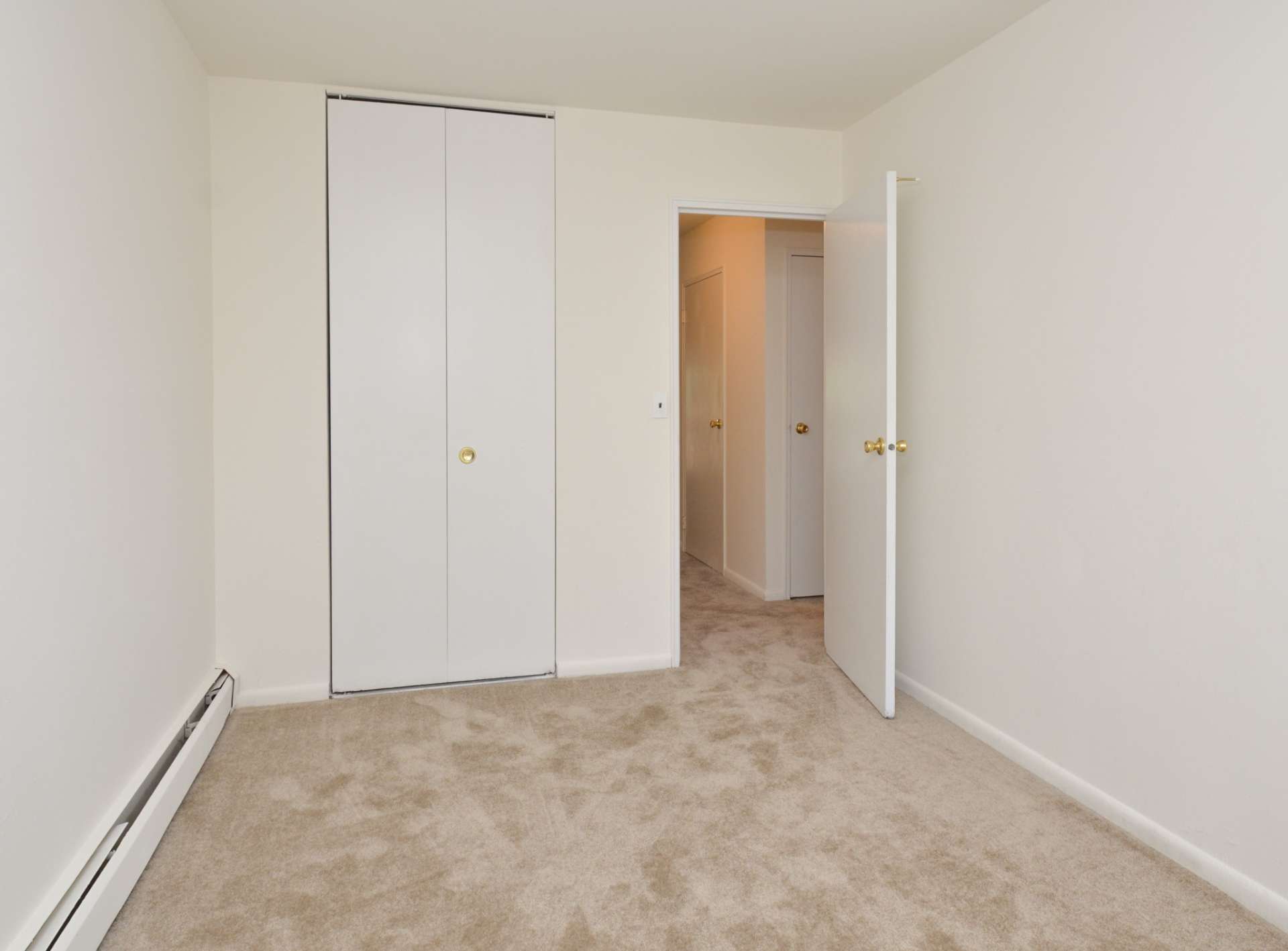 Carpeted bedroom with white walls and a closet in Lake Club Apartments.
