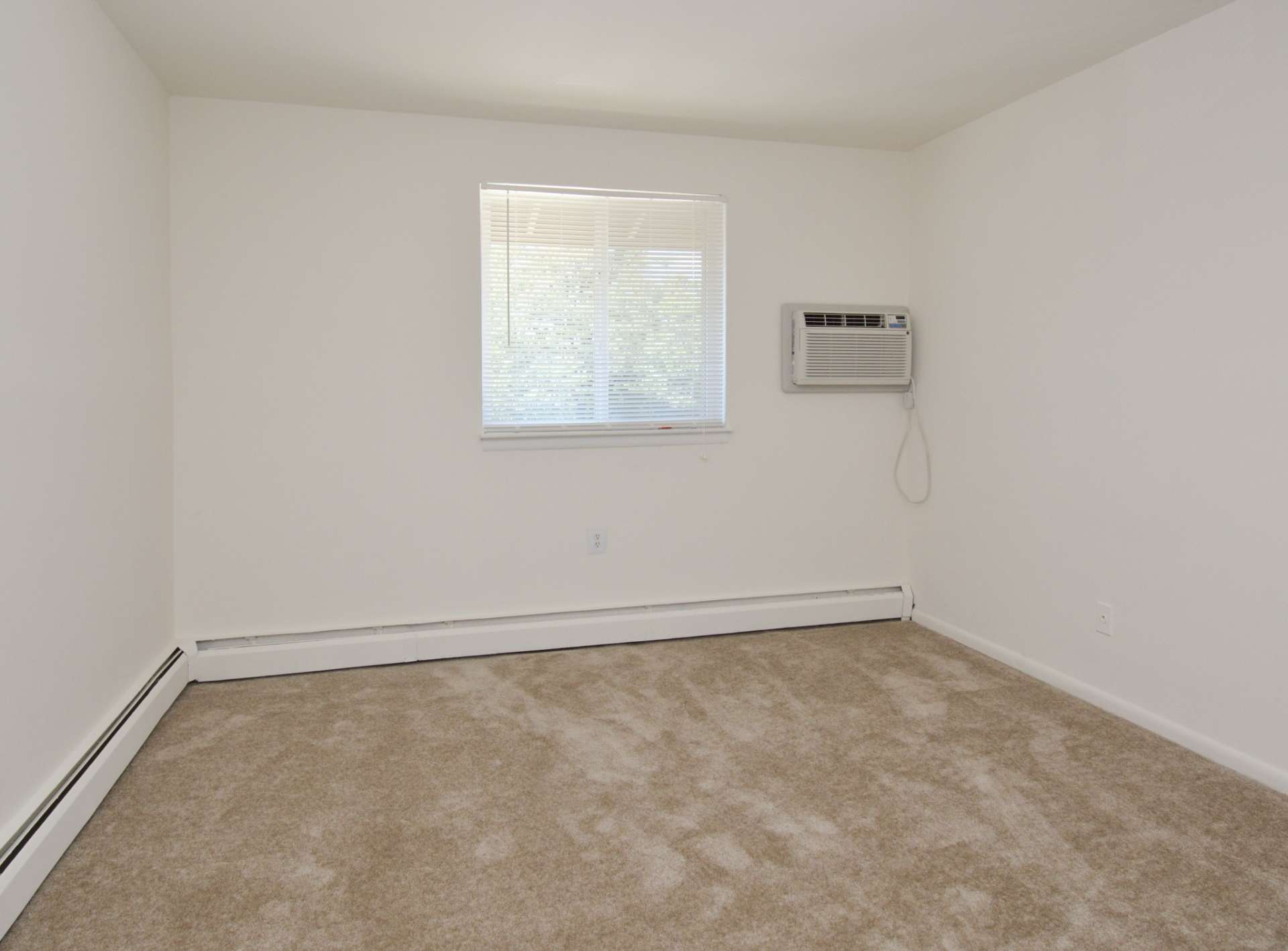 Bedroom with a window and beige carpets.