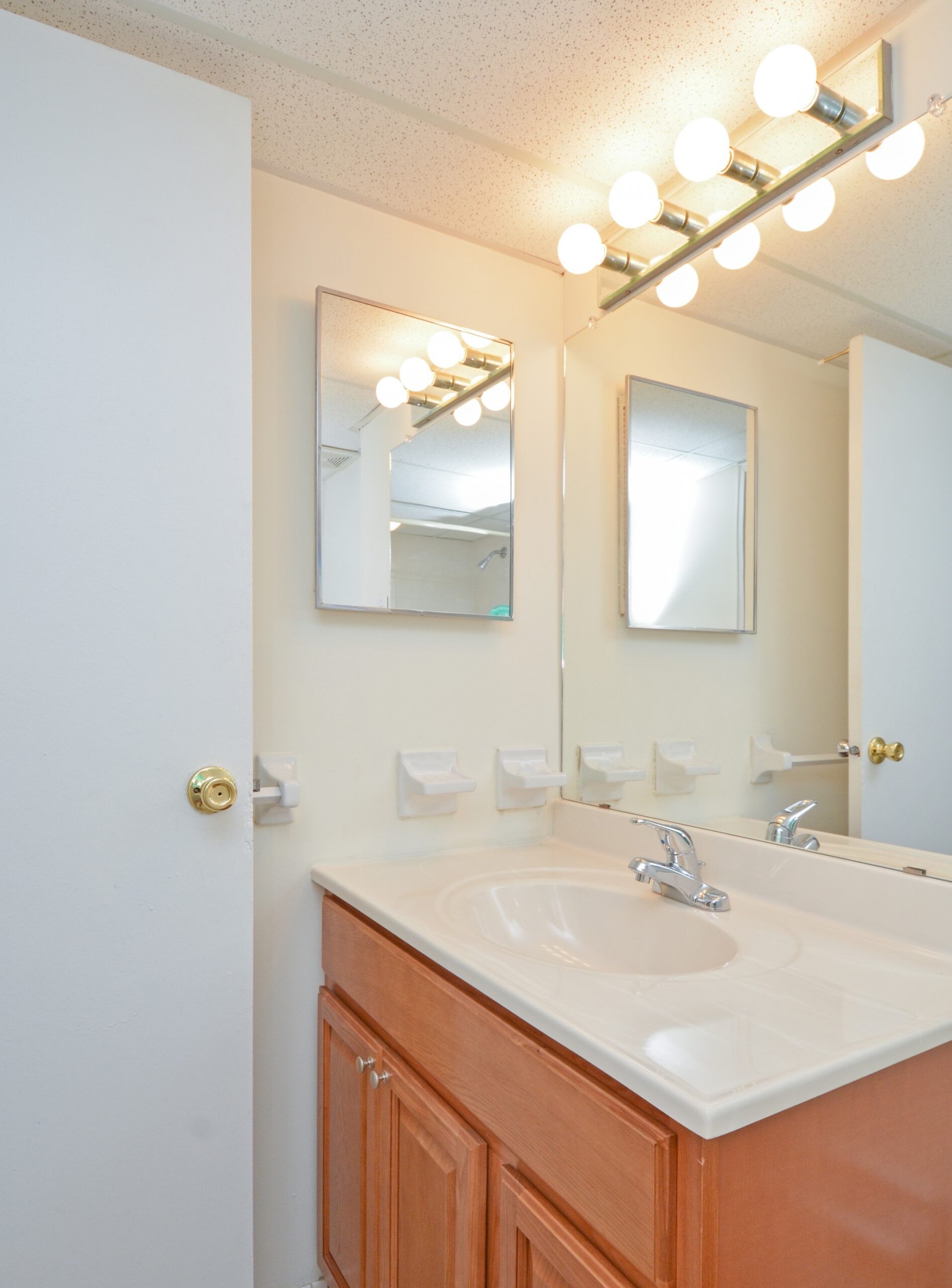 Bathroom with a large mirror in front of the sink, a small side mirror, and vanity lights.