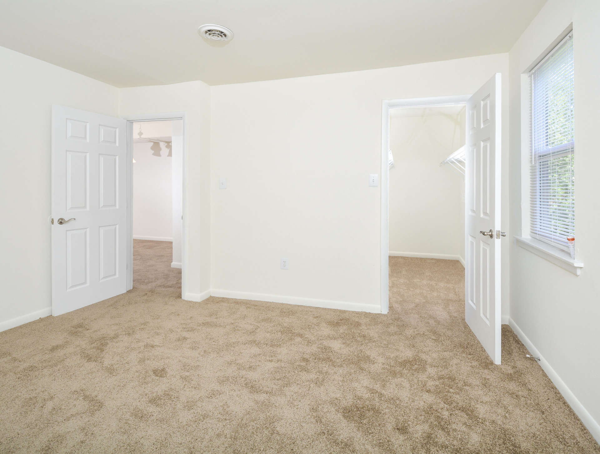 Carpeted bedroom with a walk-in closet and a window in an apartment in Newark, DE.