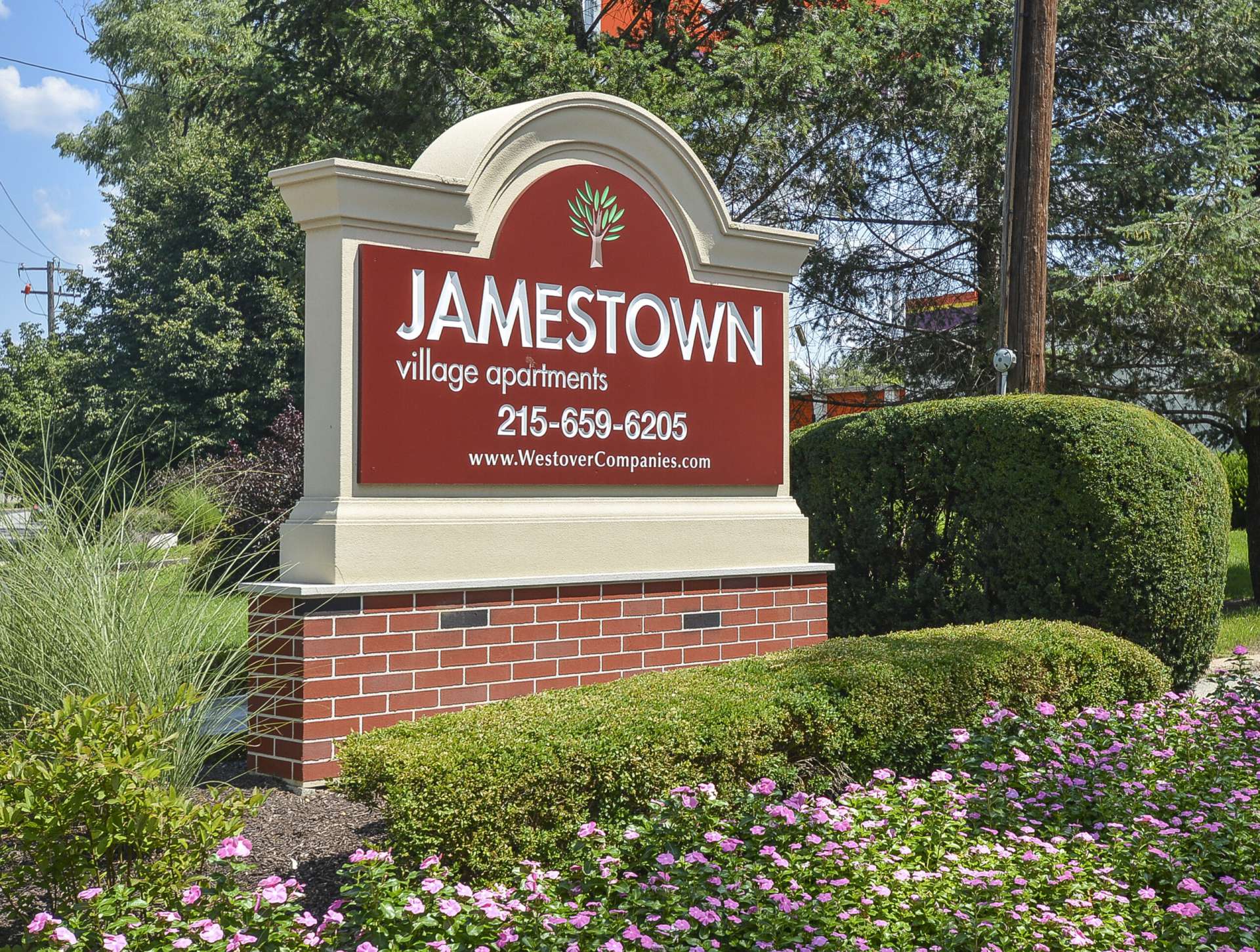 Jamestown Village Apartments sign with flowers and various bushes around the sign.