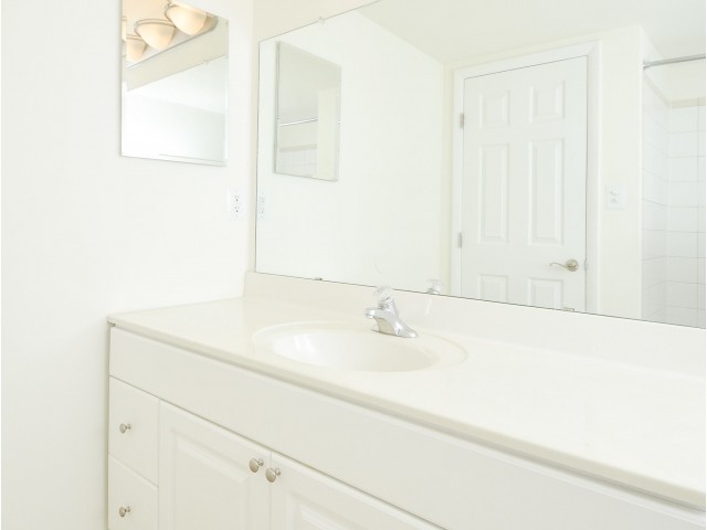 Sink with white countertops and cabinets with a large mirror in the bathroom.