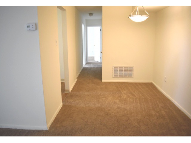Dining area of an apartment unfurnished, fitted with carpet flooring, and lighting
