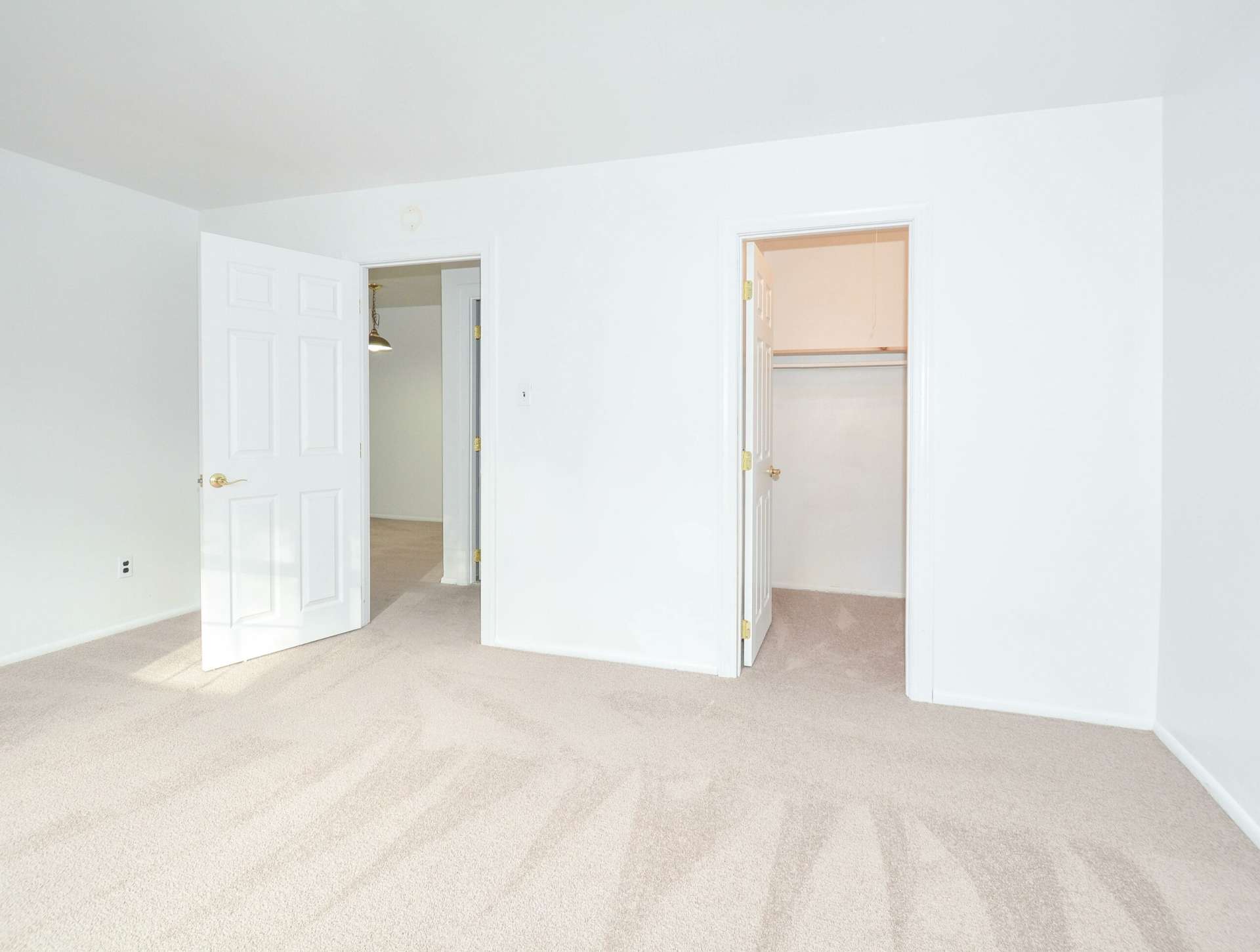 Bedroom with beige carpet, a closet, and white walls.