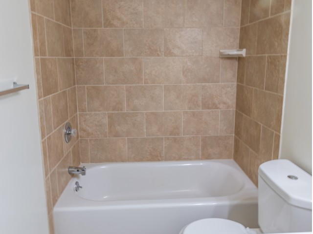 Bathtub with light brown tiles.